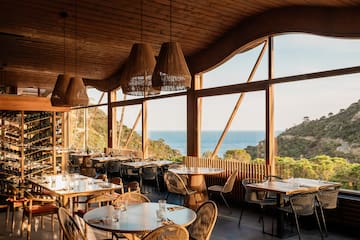 a room with tables and chairs and a view of the ocean