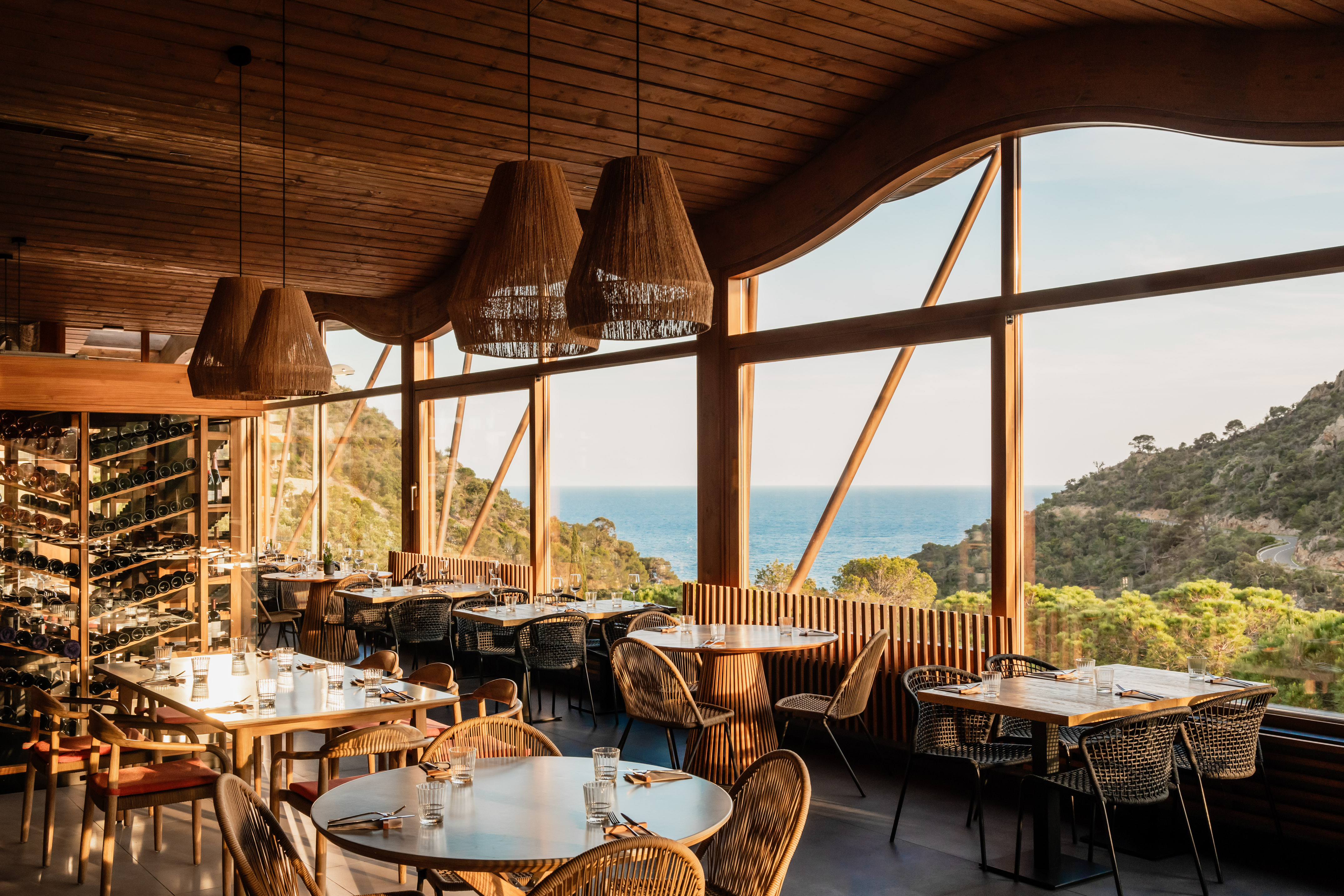 Restaurant with panoramic ocean view, modern wood interior, and dining tables.