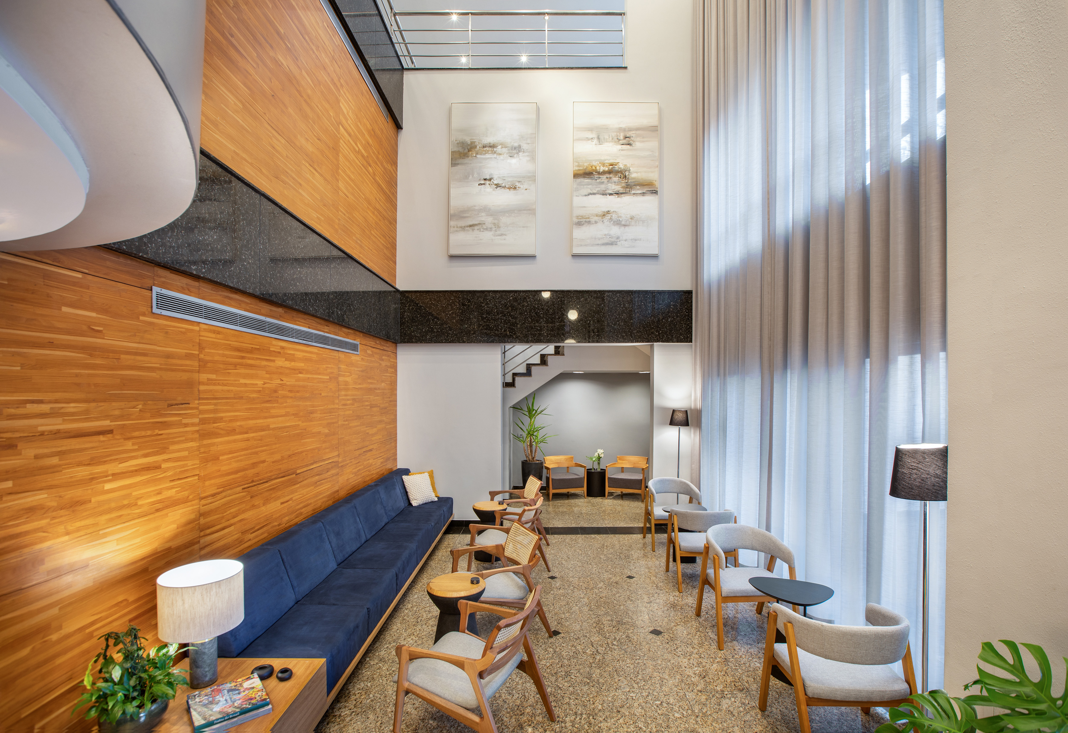 Modern hotel lounge with wood paneling, blue sofa, and comfortable chairs.