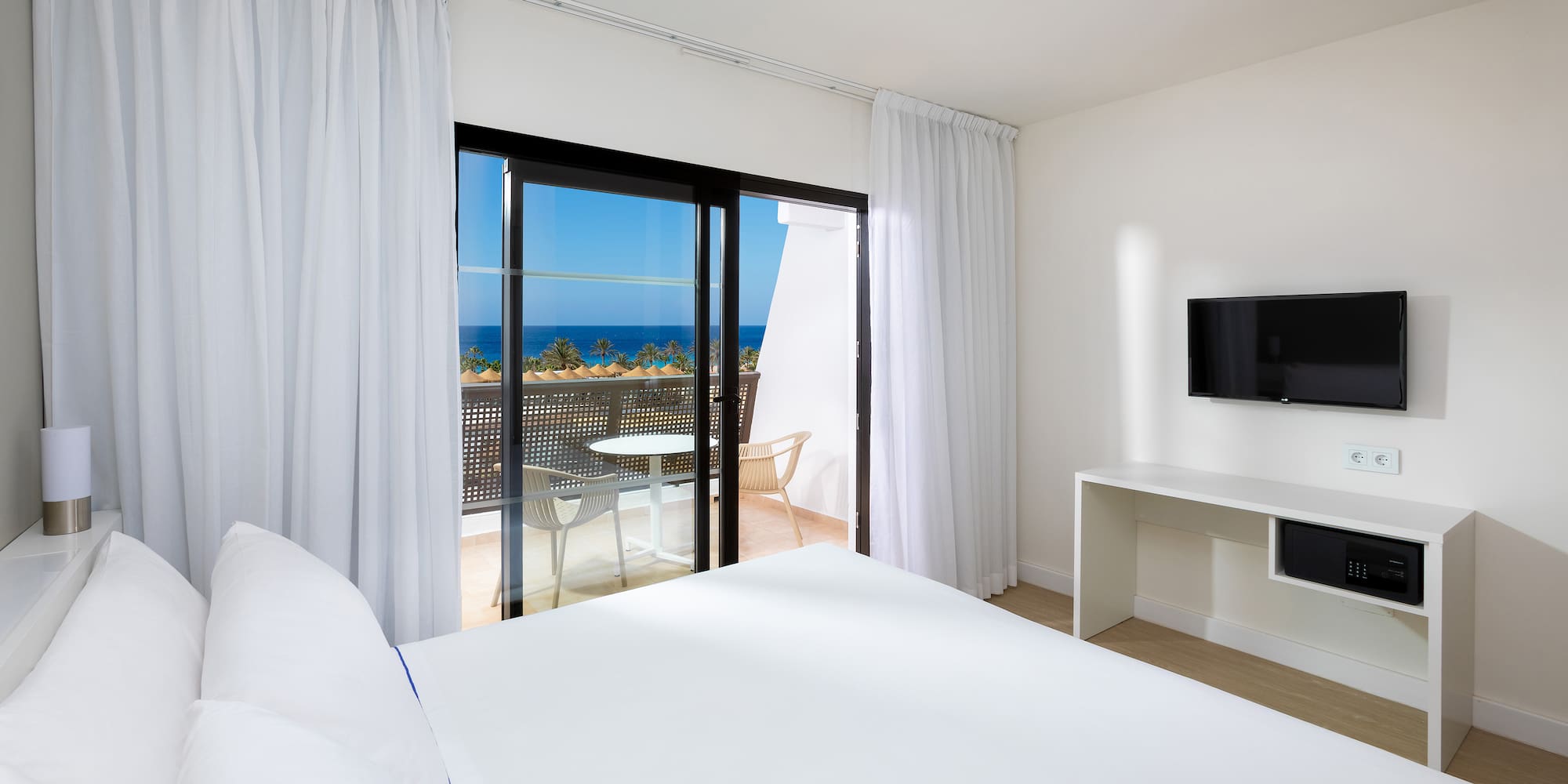 a bedroom with a television and a view of the ocean