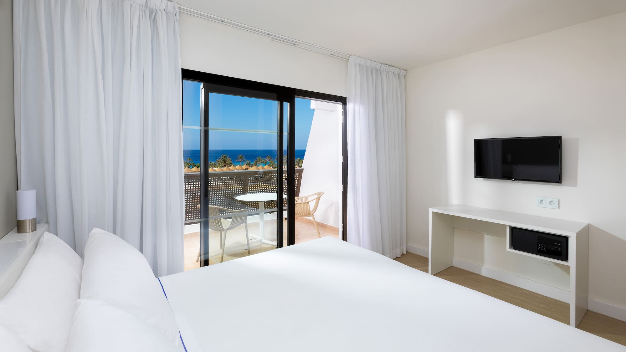 a bedroom with a television and a view of the ocean