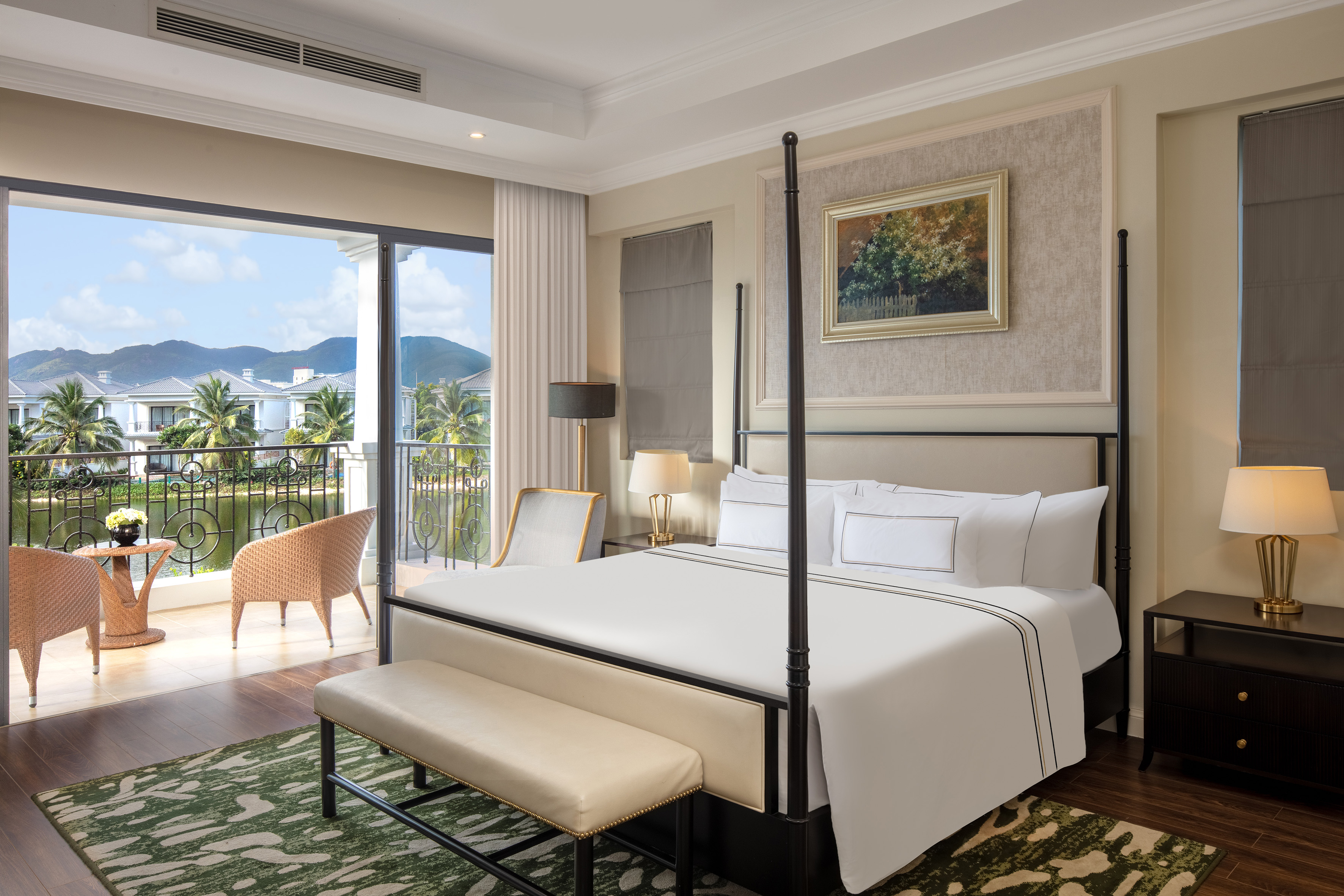 Luxury bedroom with four-poster bed, balcony, and scenic tropical resort view.