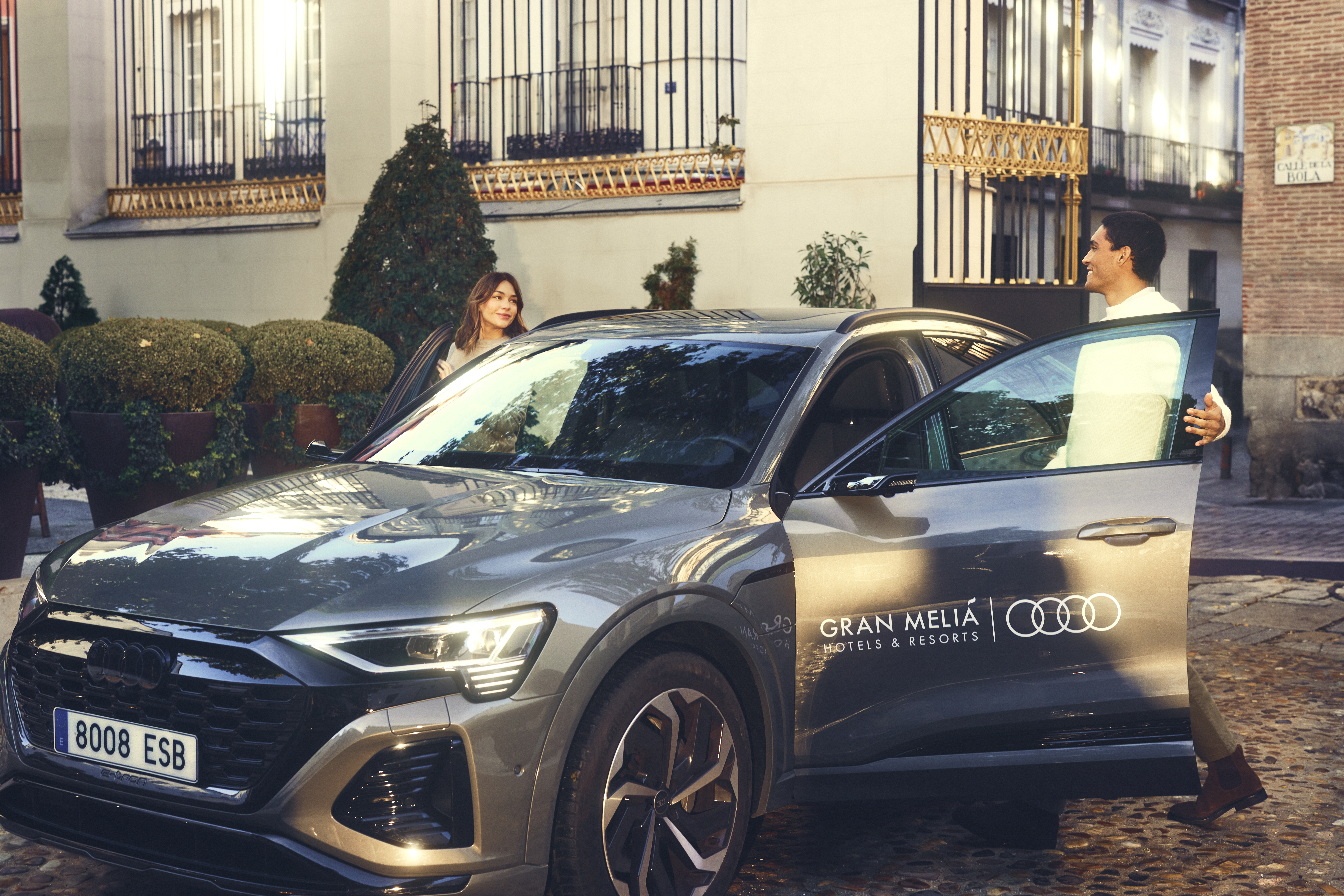 Couple entering Gran Melia branded Audi e-tron luxury SUV in a city.