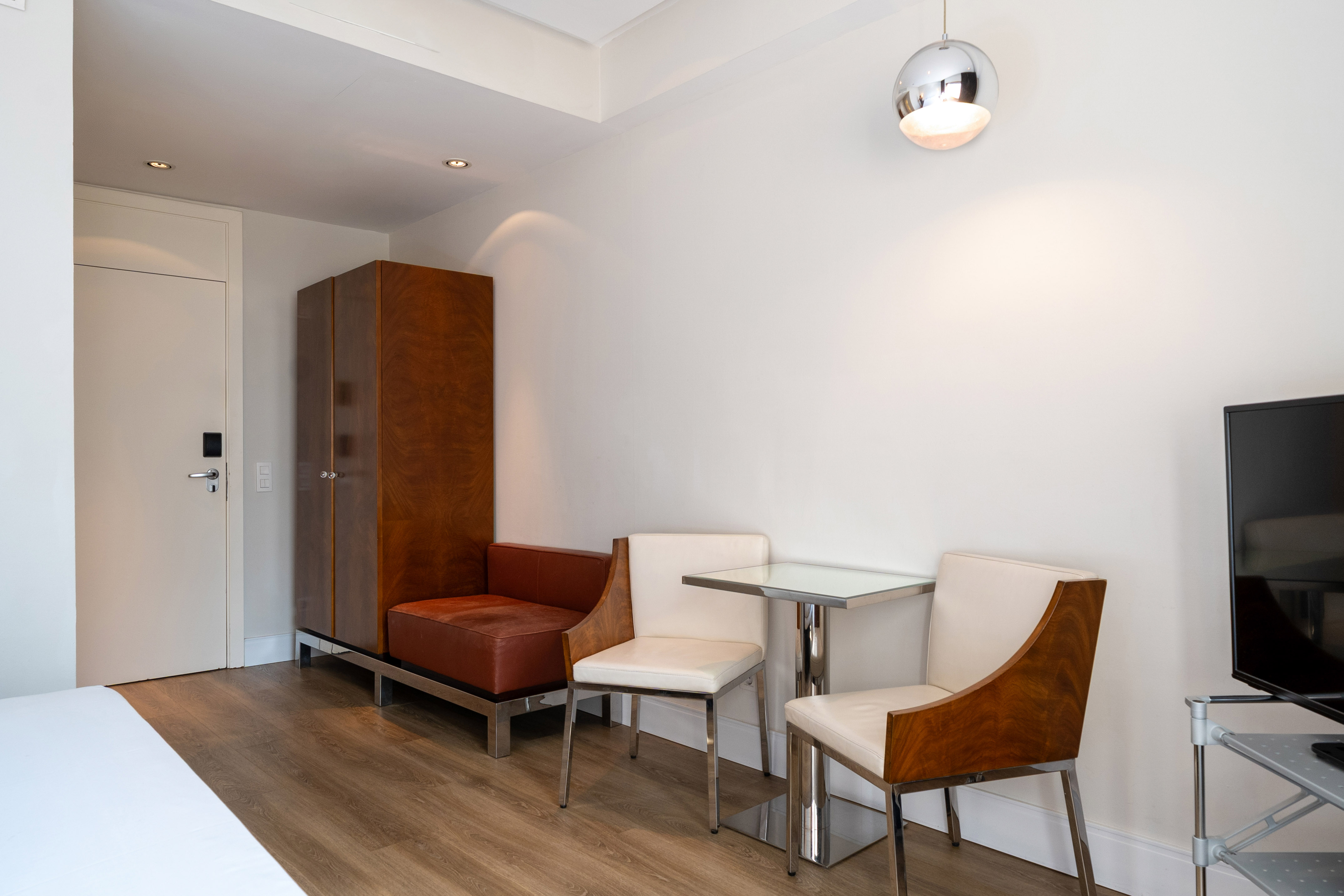 Modern studio apartment with dining area, wooden floors, and elegant furniture.
