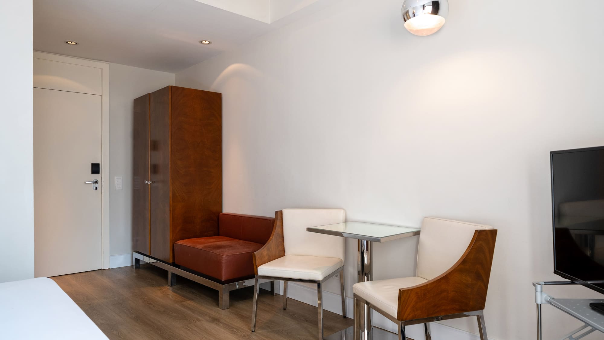 Modern studio apartment with dining area, wooden floors, and elegant furniture.