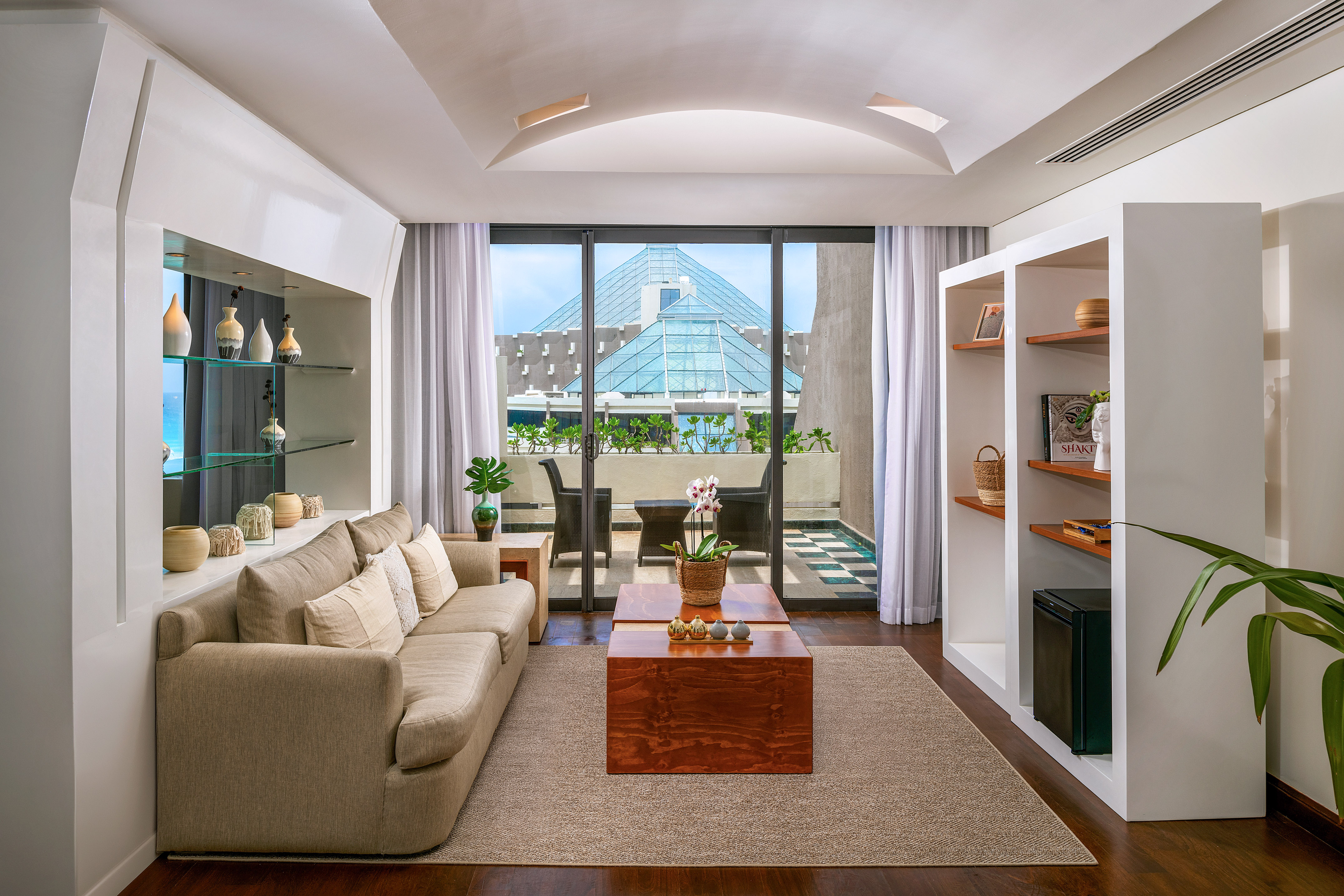 Modern living room, sofa, balcony with glass pyramid building view.