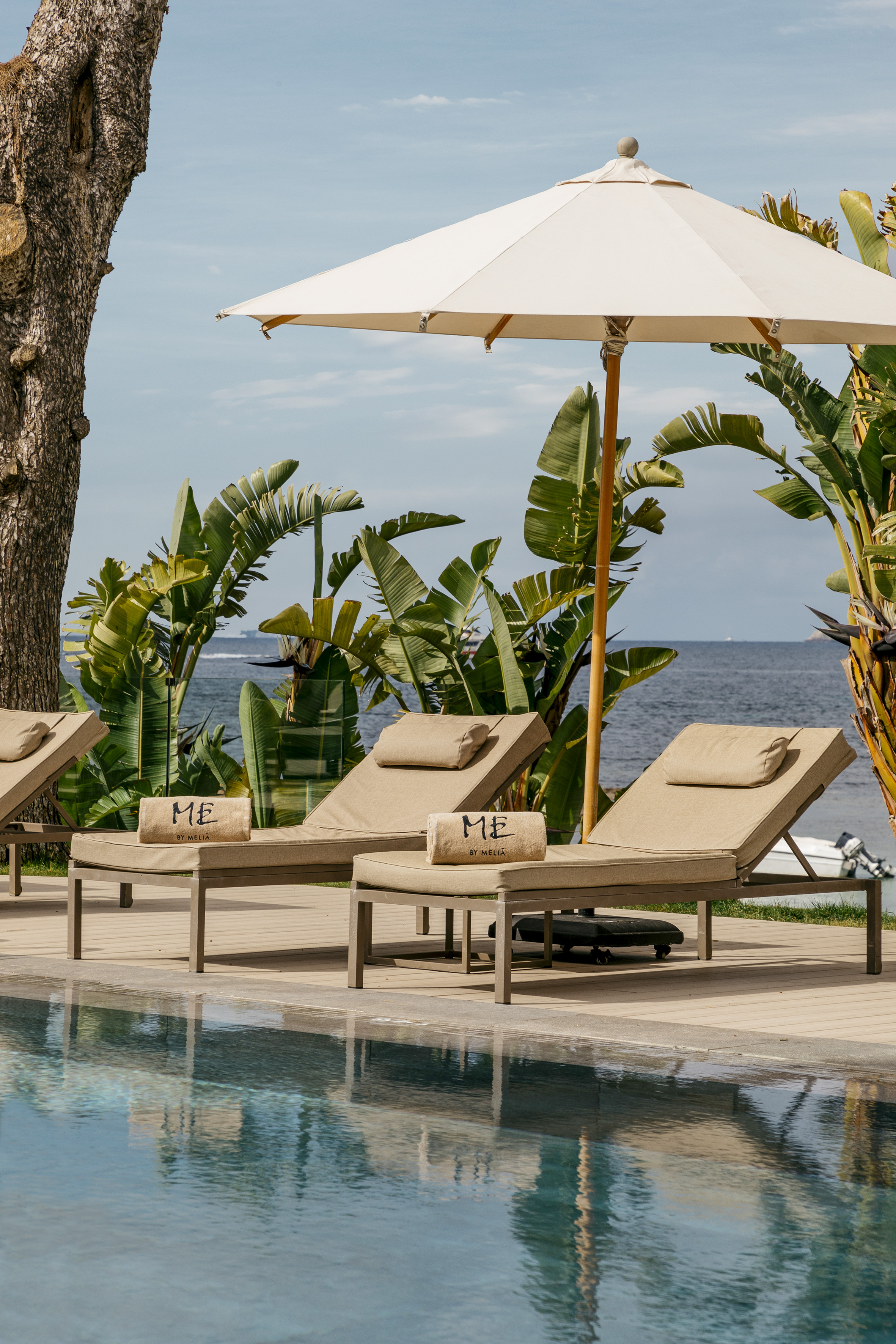 a pool with chairs and umbrella by the water