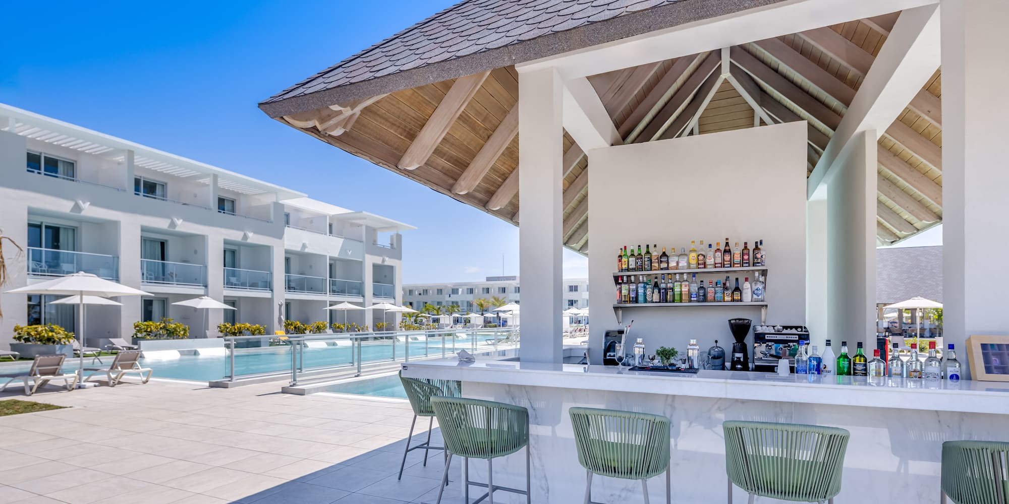 a bar with drinks and chairs by a pool
