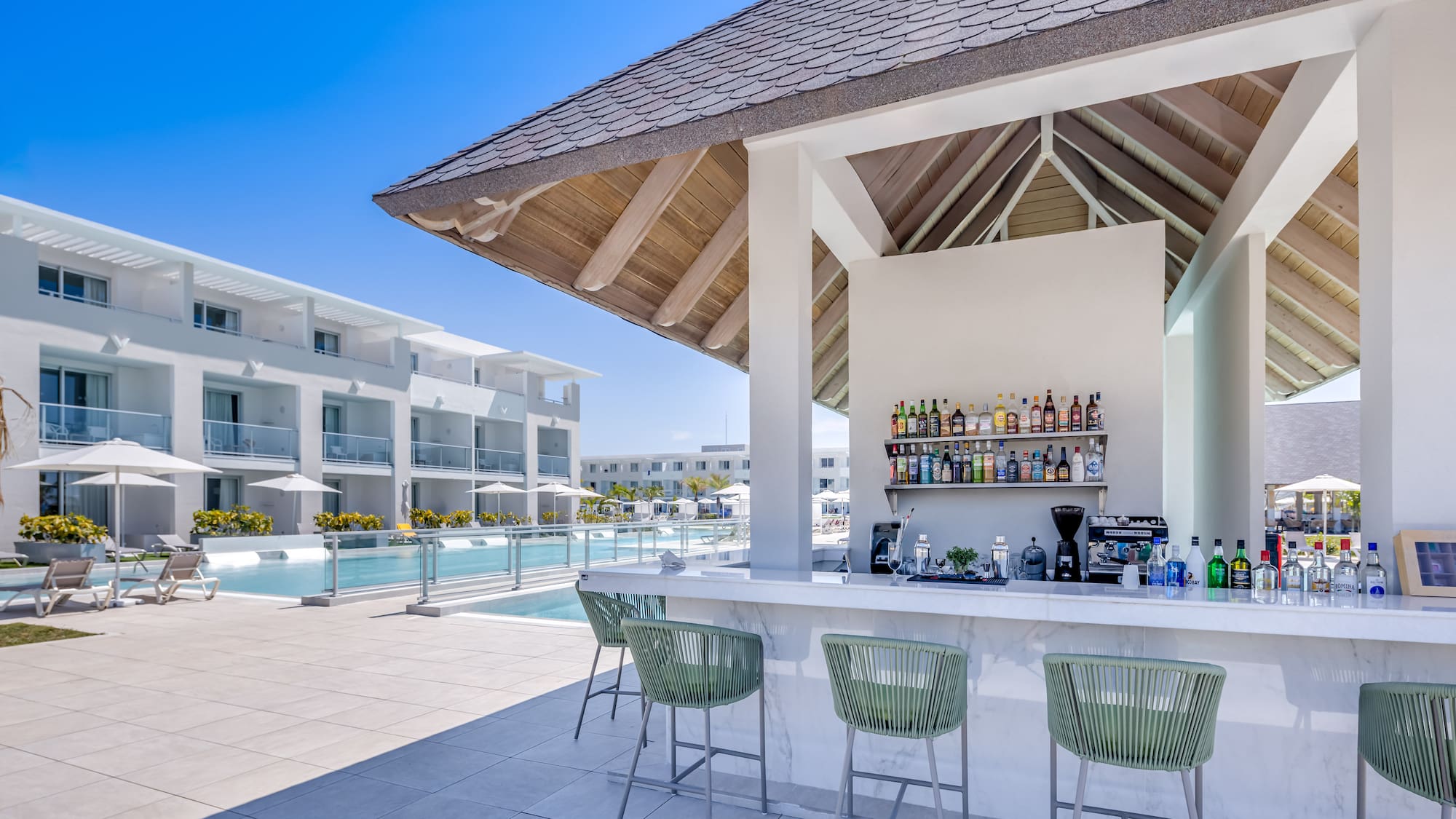 a bar with drinks and chairs by a pool
