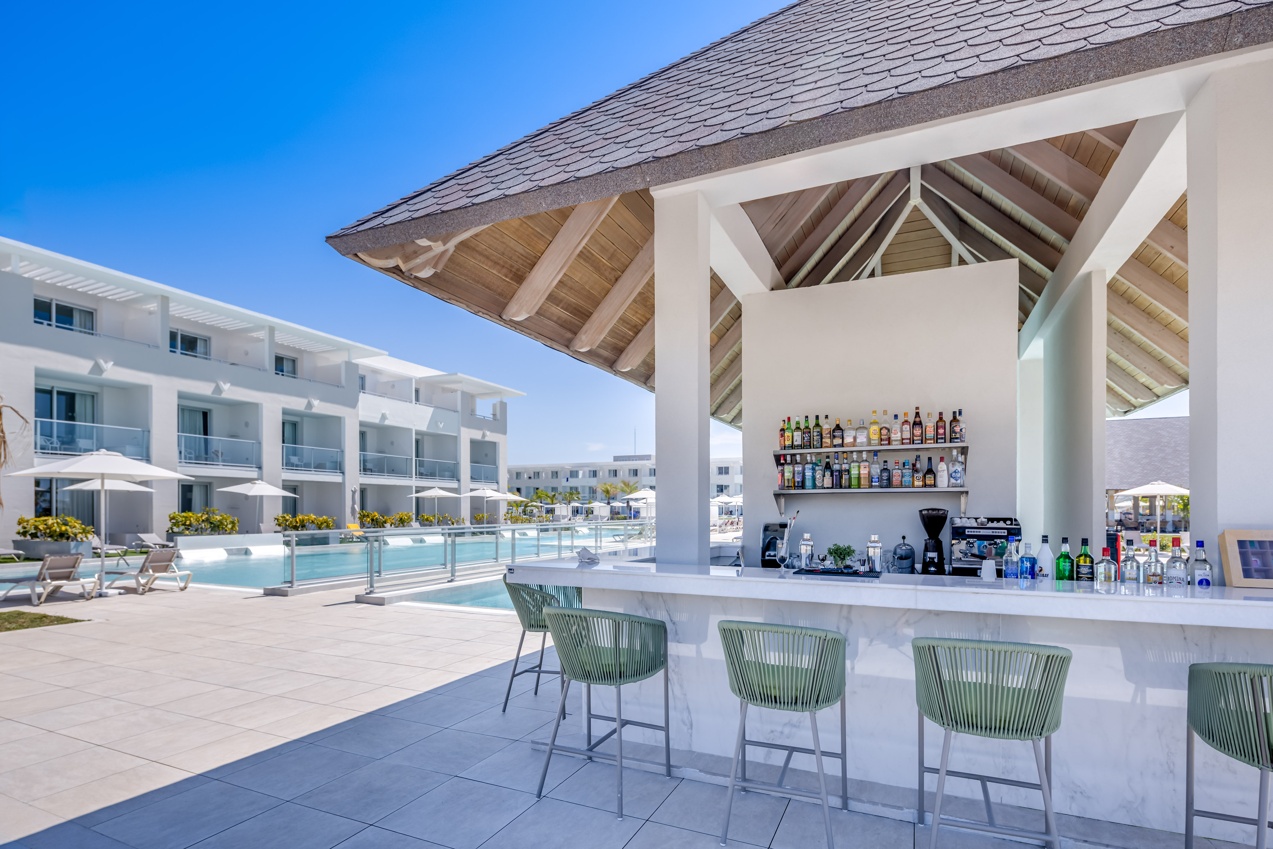 a bar with drinks and chairs by a pool