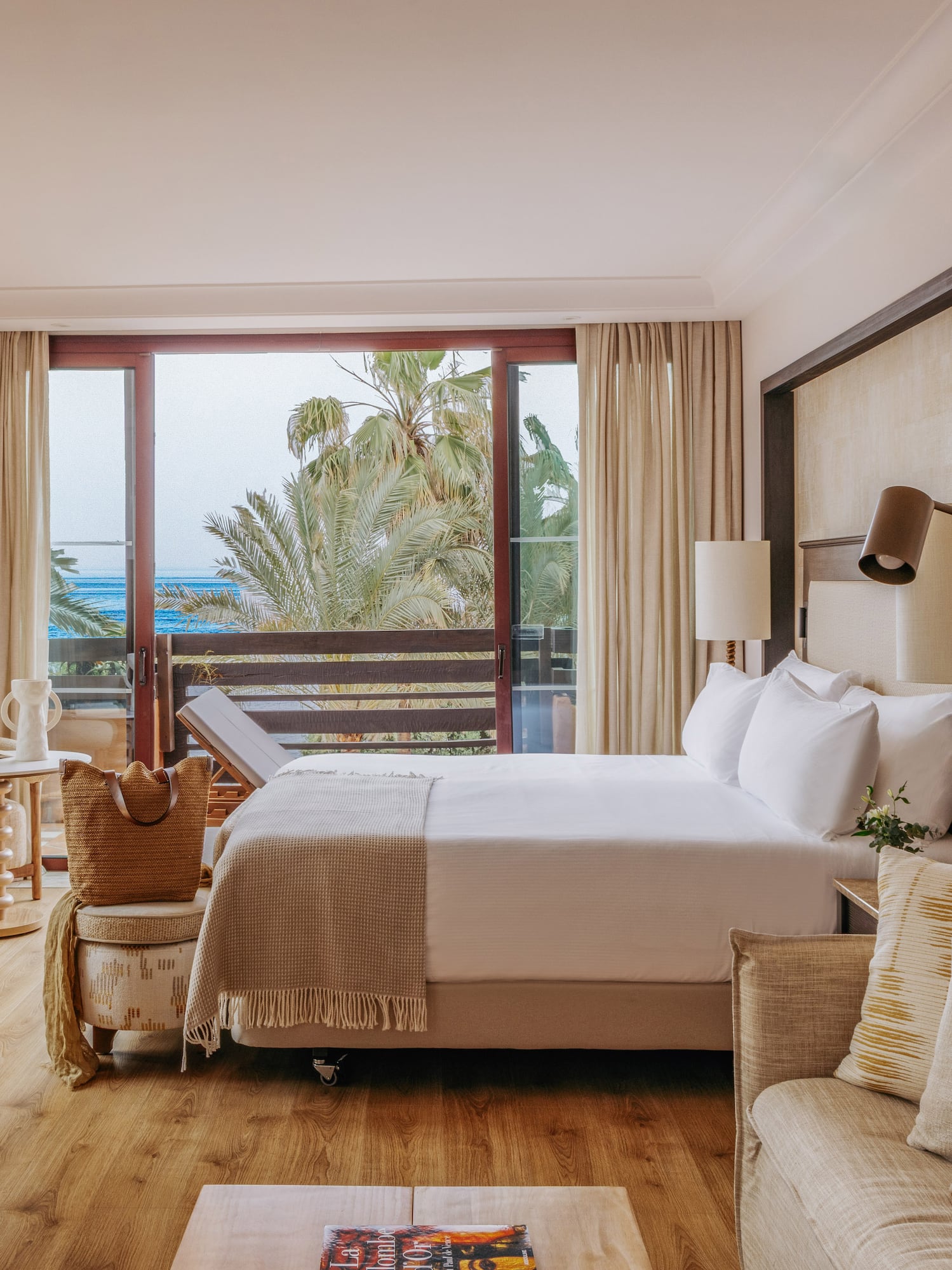 Luxury hotel room with ocean view balcony, bed, and sofa.