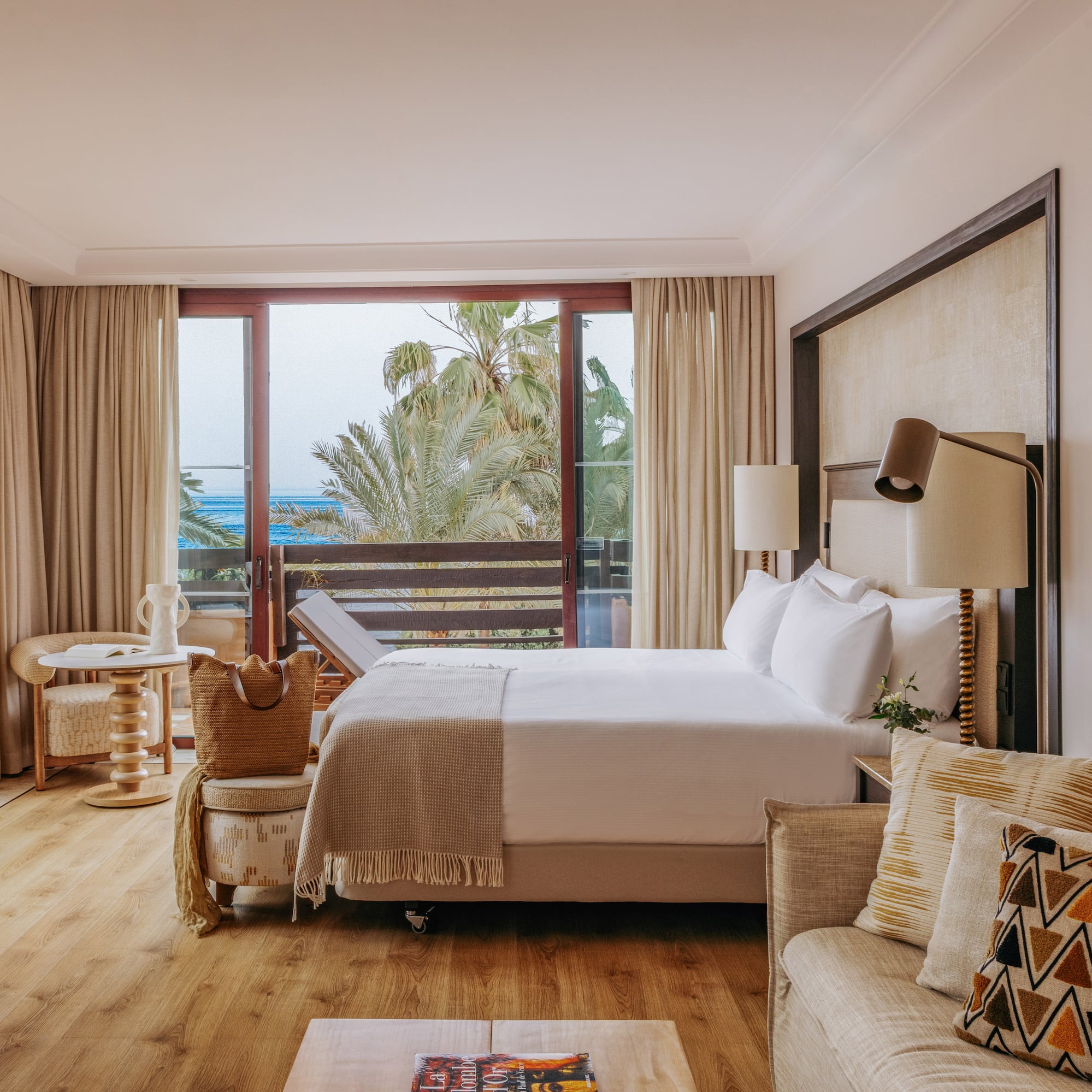 Oceanfront luxury hotel room with balcony, king bed, and comfortable sofa.