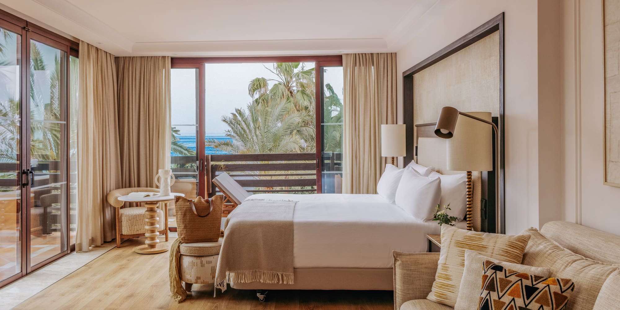 Oceanfront luxury hotel room with balcony, king bed, and comfortable sofa.