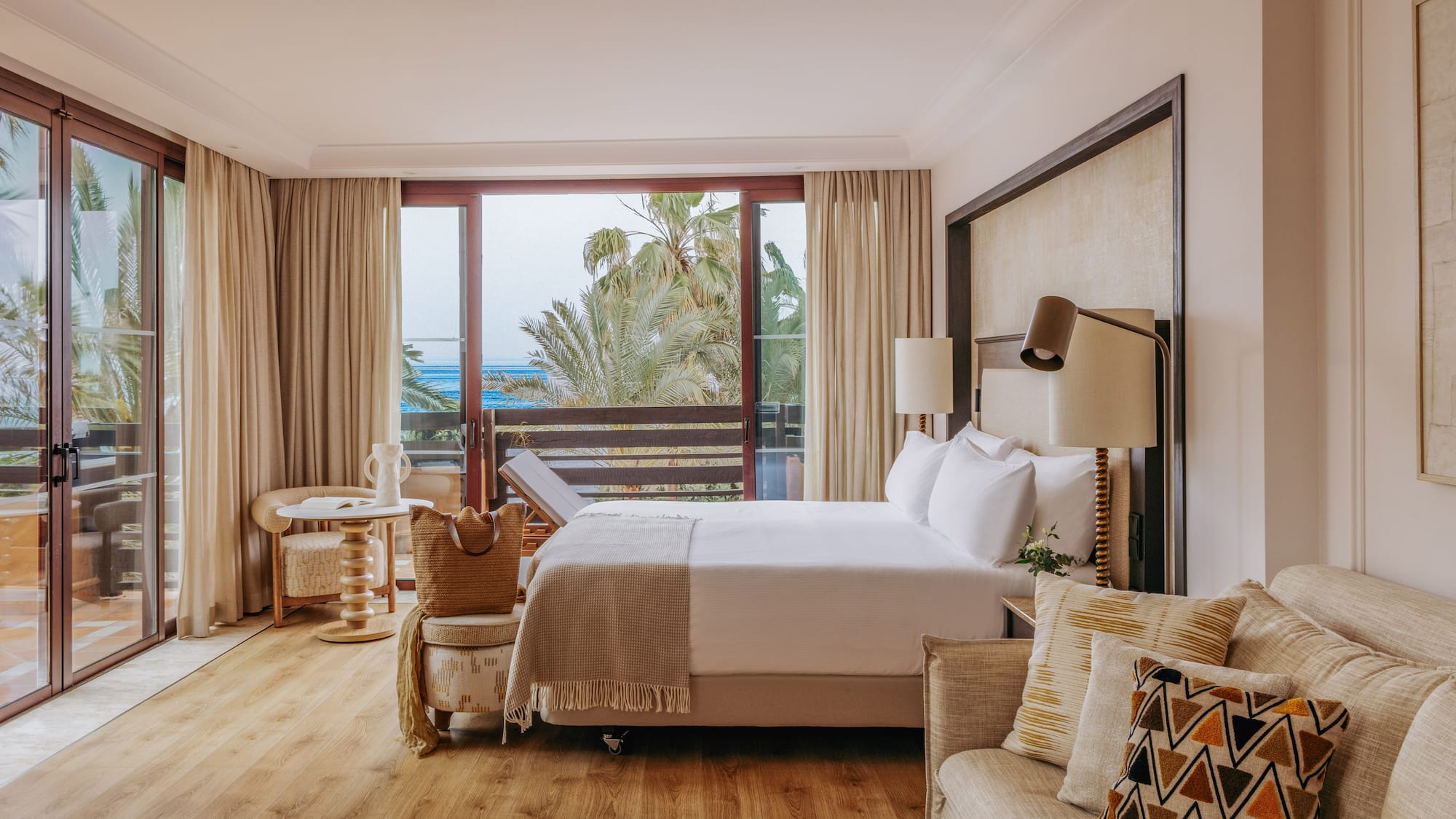 Oceanfront luxury hotel room with balcony, king bed, and comfortable sofa.