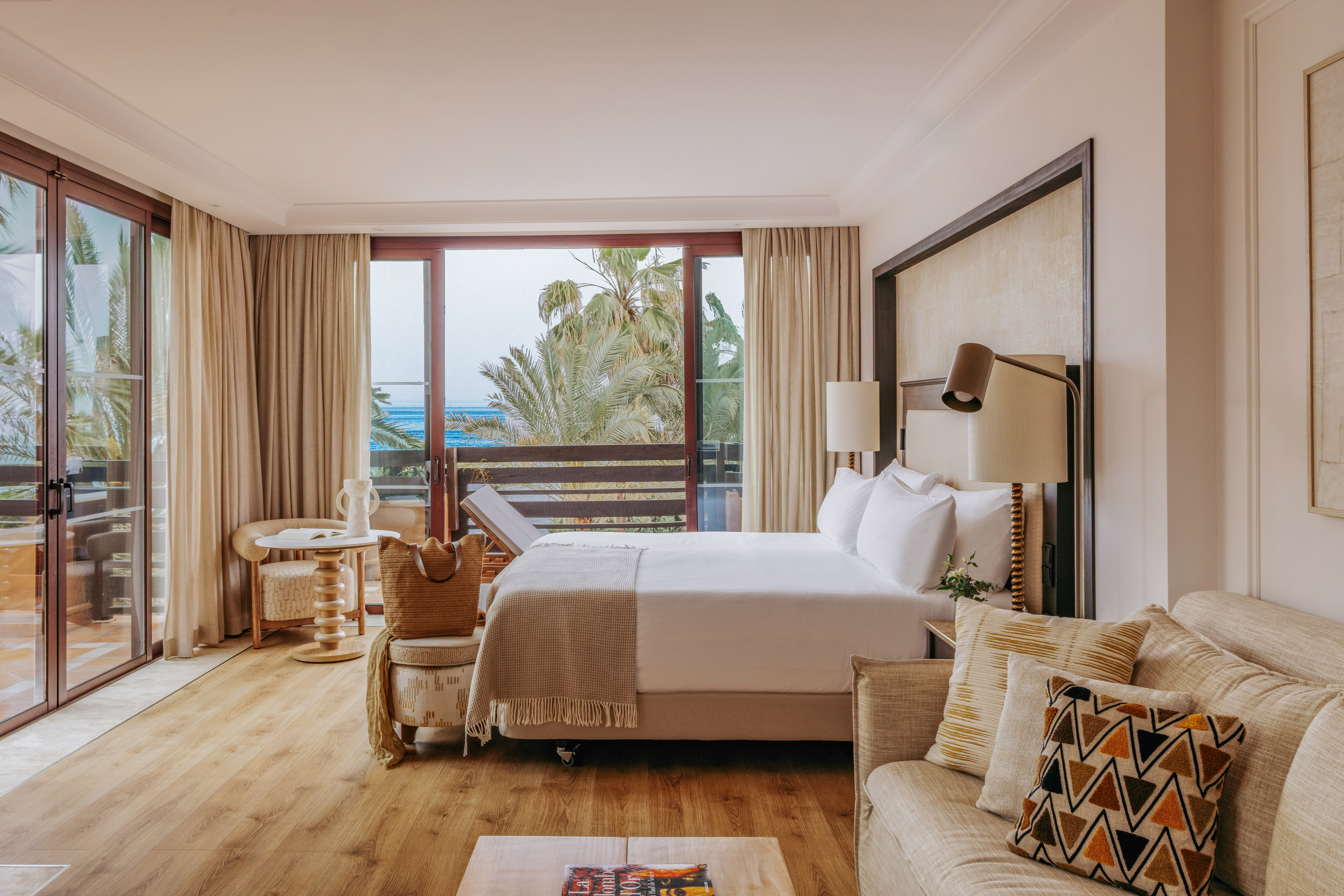 Oceanfront luxury hotel room with balcony, king bed, and comfortable sofa.