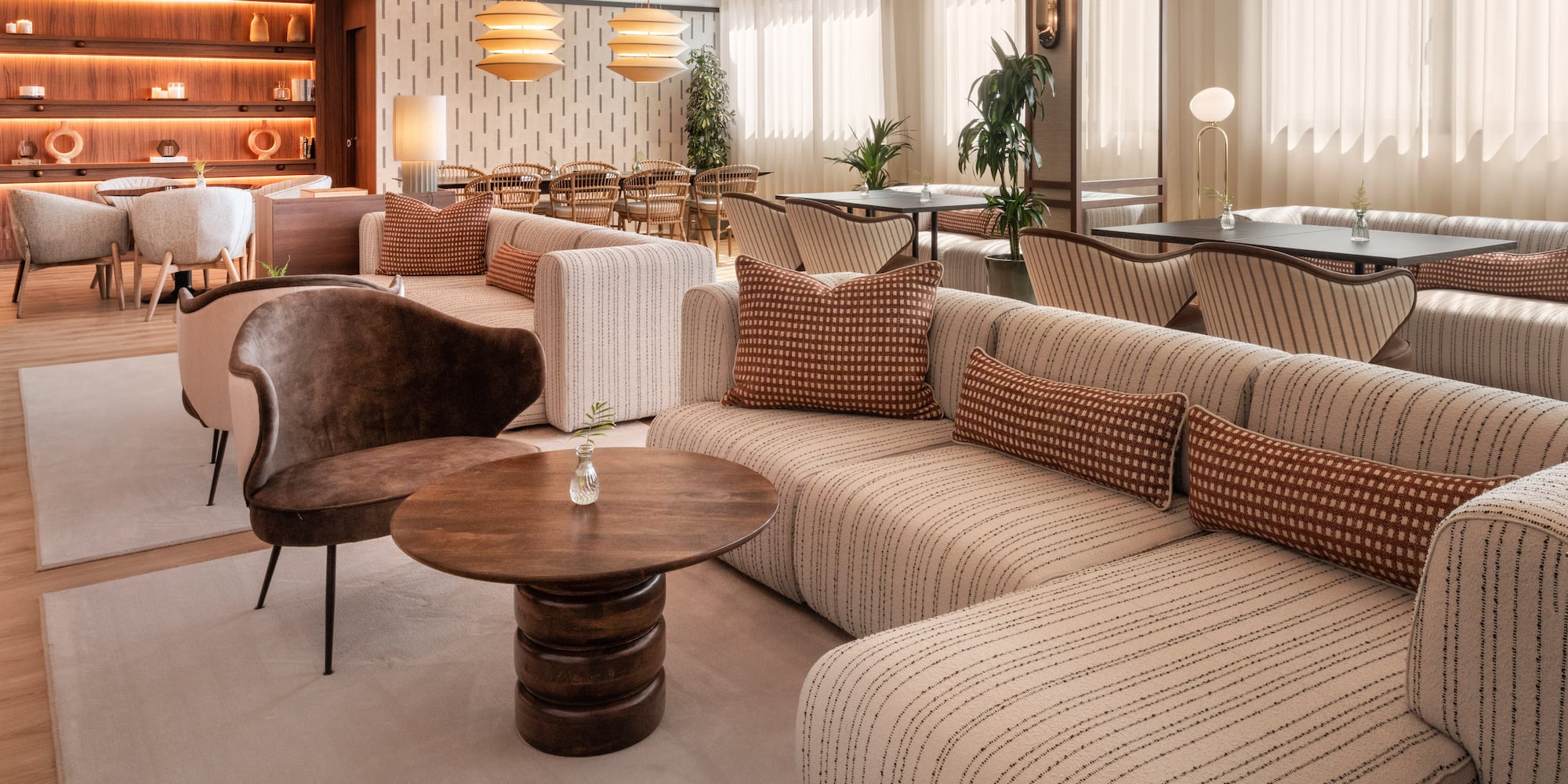 Lobby moderno con sofás de rayas, mesas de madera y estantes iluminados.