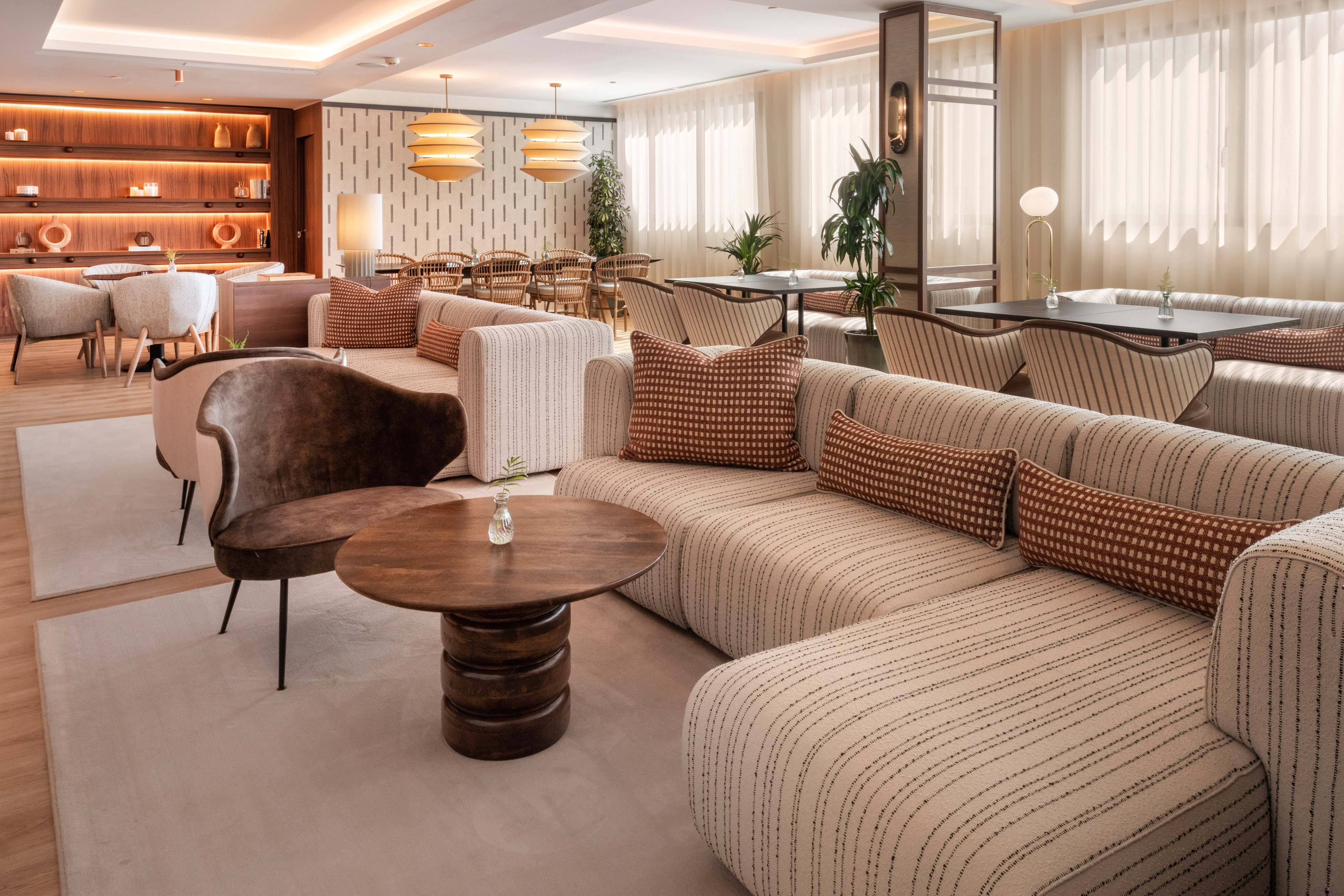 Lobby moderno con sofás de rayas, mesas de madera y estantes iluminados.