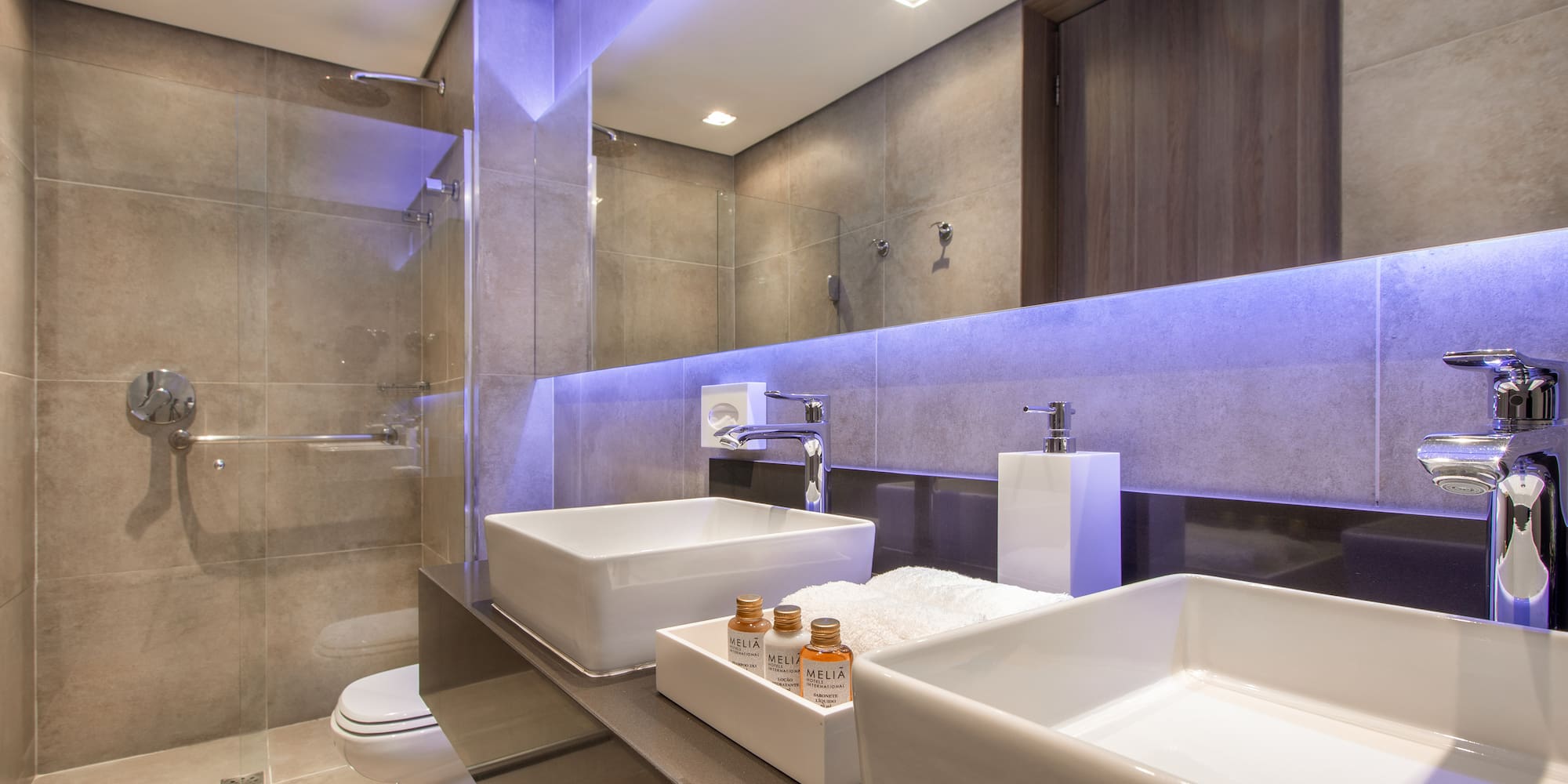 a bathroom with a glass shower and two sinks