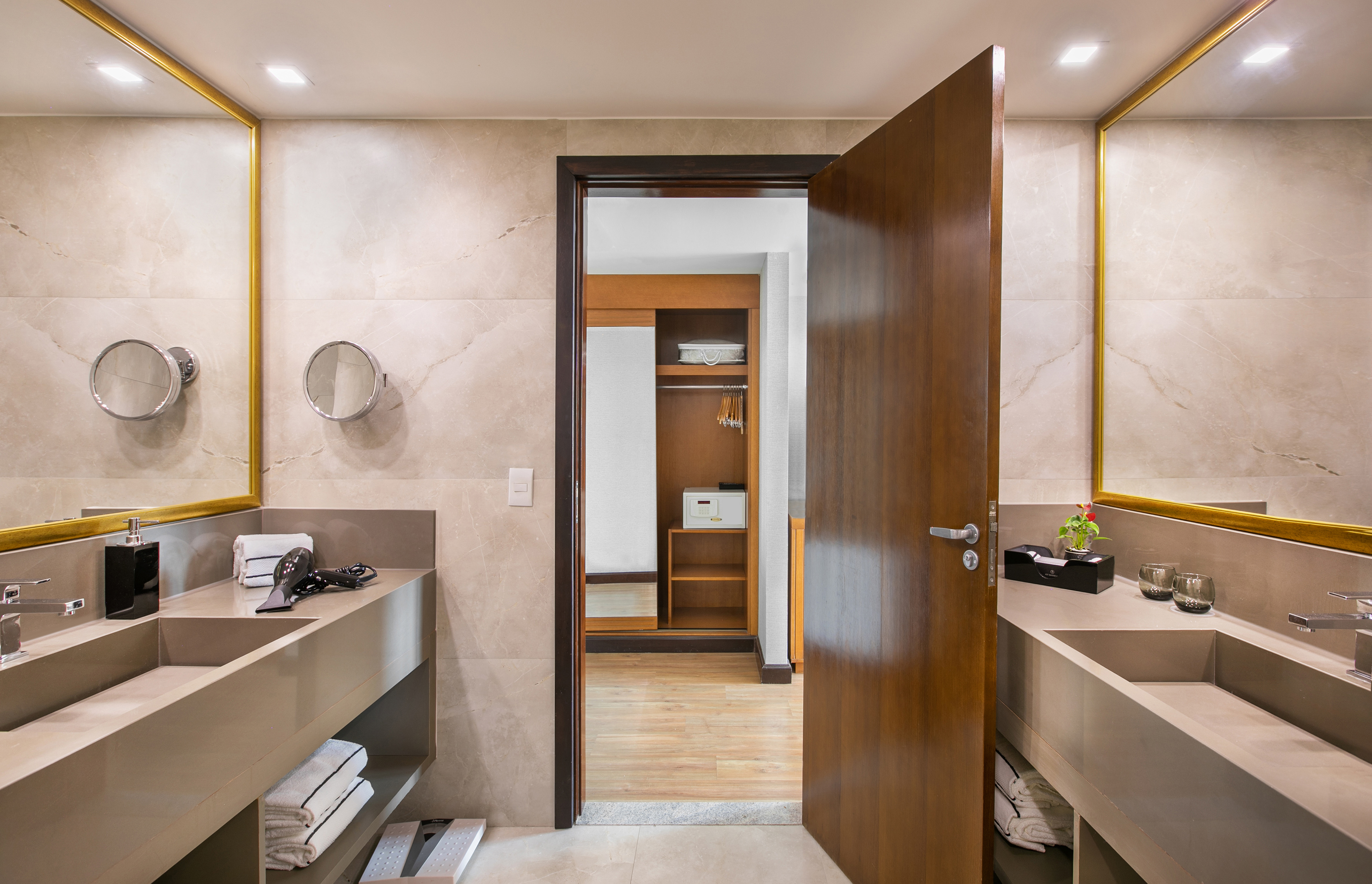 Modern bathroom: double vanity, gold mirrors, open closet with safe.