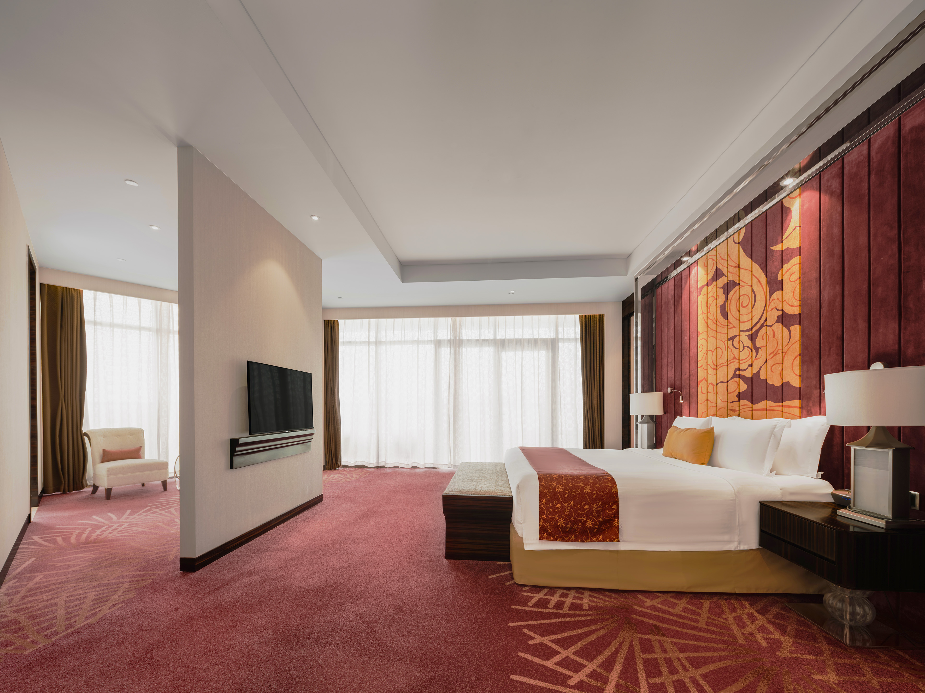 Luxury hotel suite with king bed, red carpet, and Asian-inspired decor.