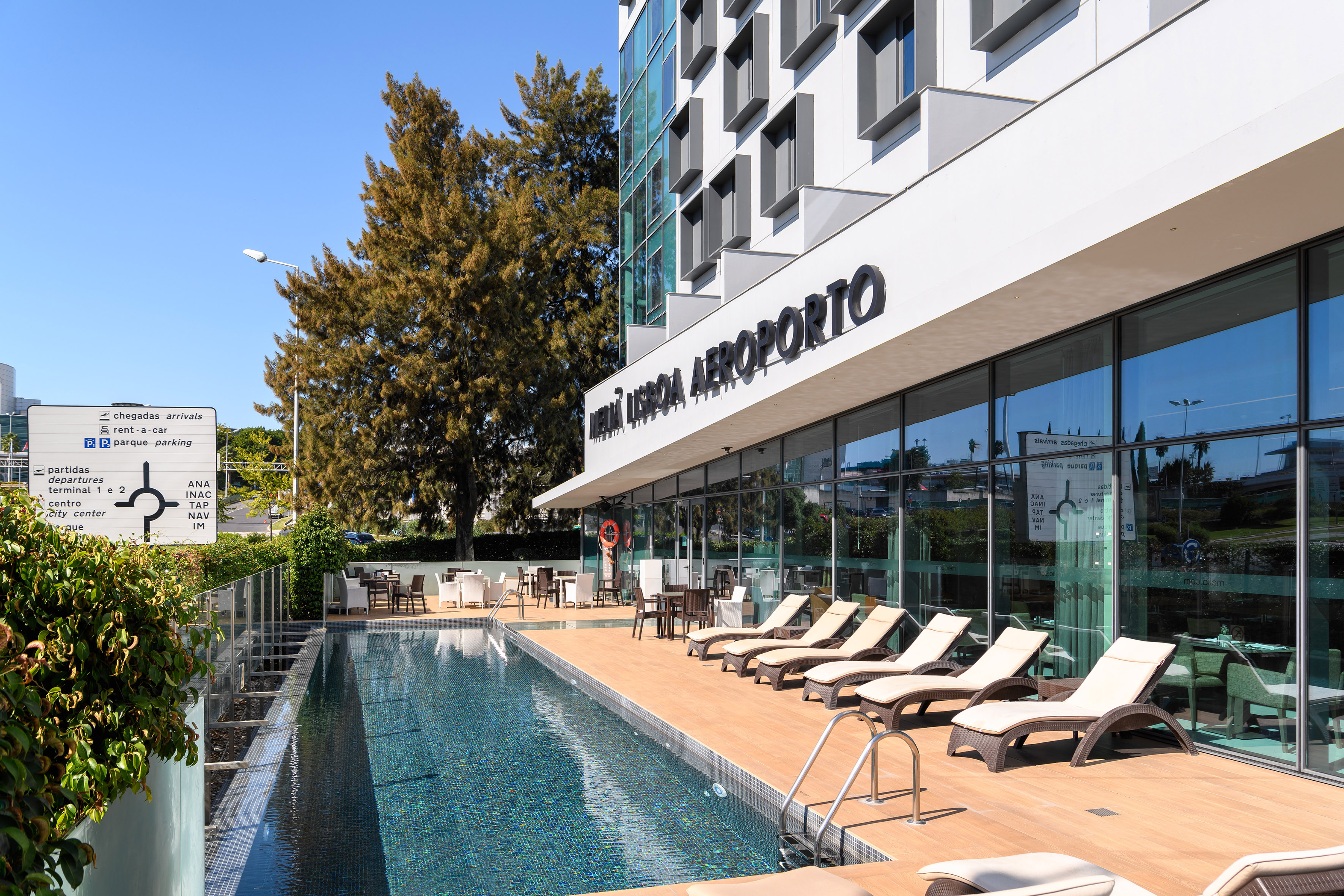 Lisbon Airport hotel with outdoor pool, lounge deck, and directional sign.