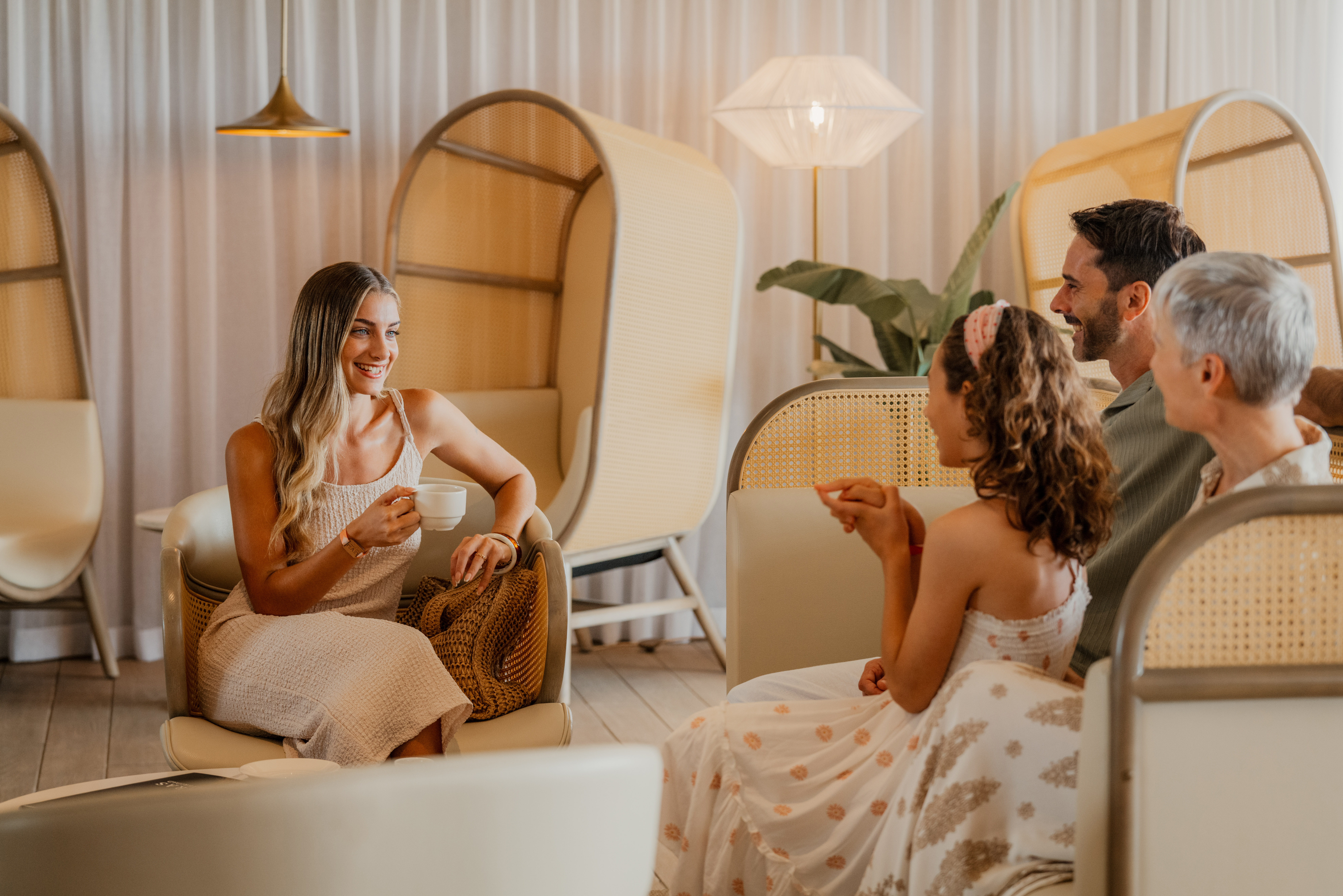 Guests relaxing and conversing in a hotel lounge with modern rattan chairs.