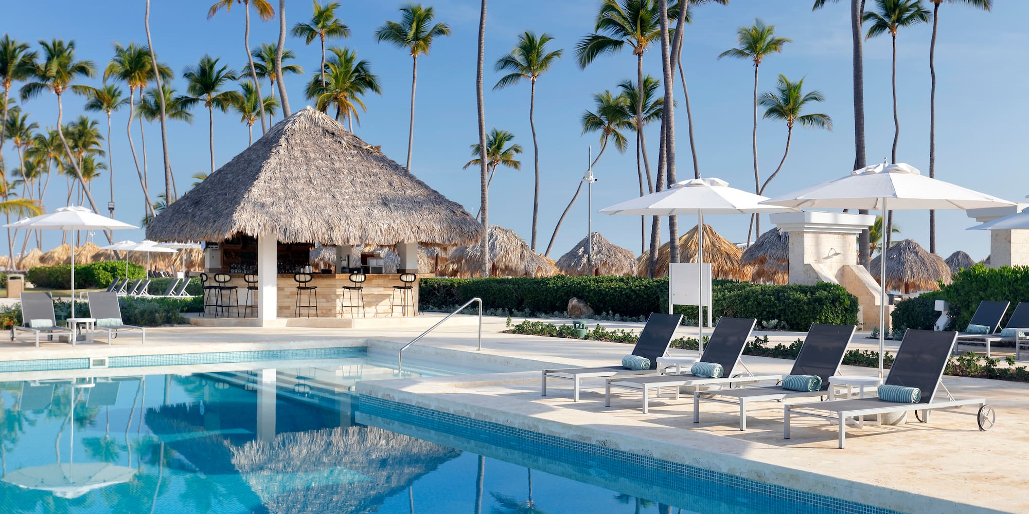 a pool with chairs and umbrellas by a bar
