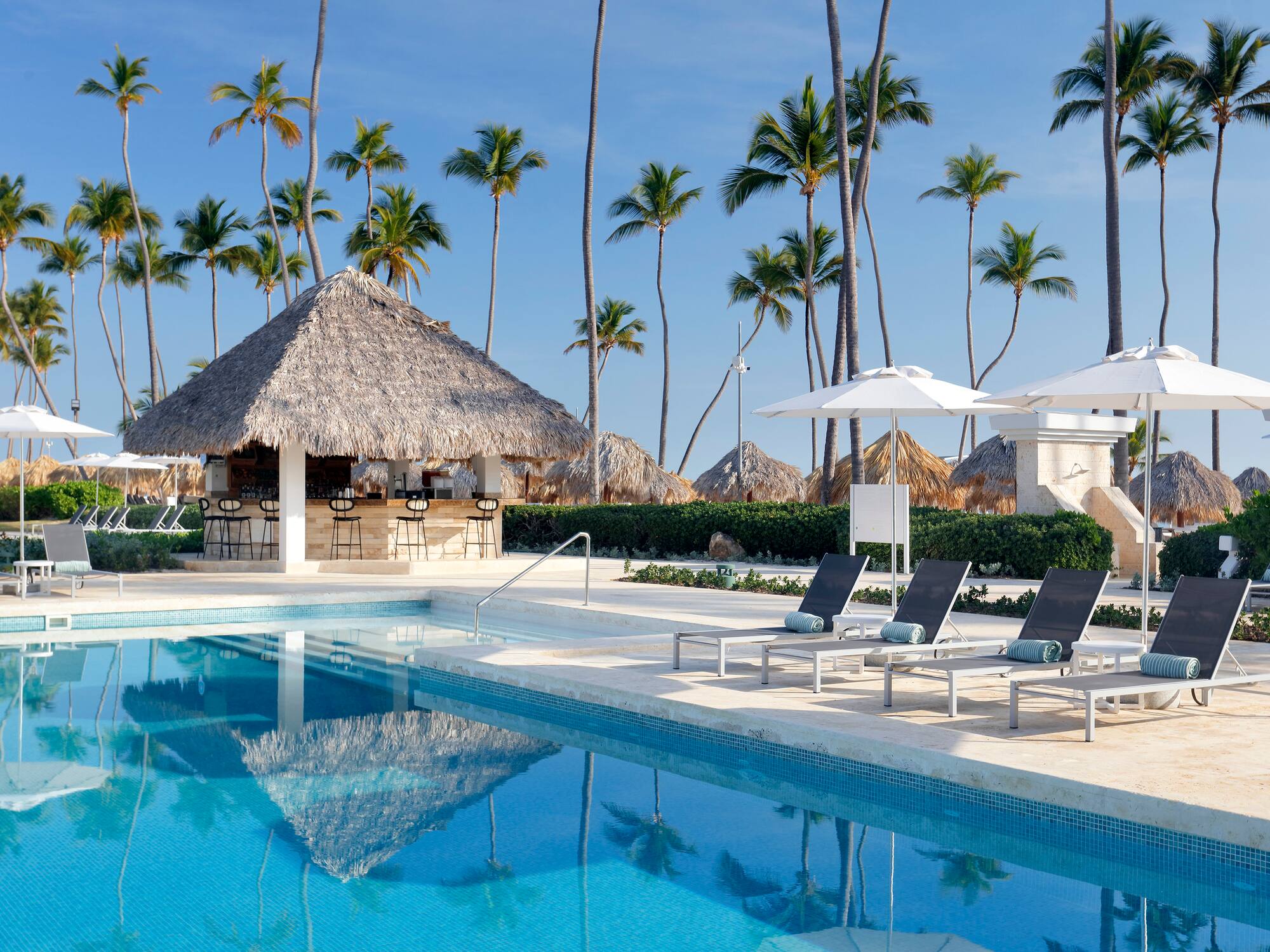 a pool with chairs and umbrellas by a bar