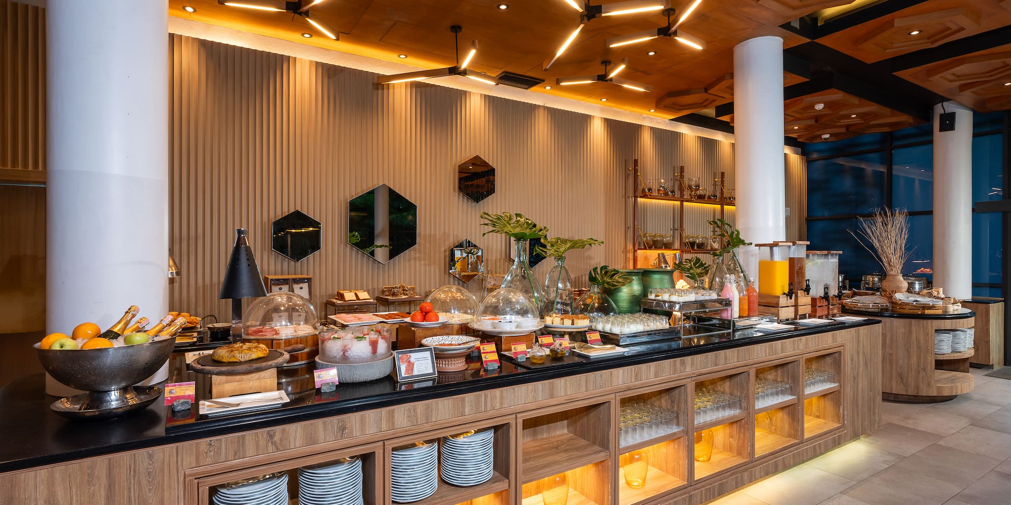Modern hotel buffet breakfast with fresh fruits, pastries, and juices.