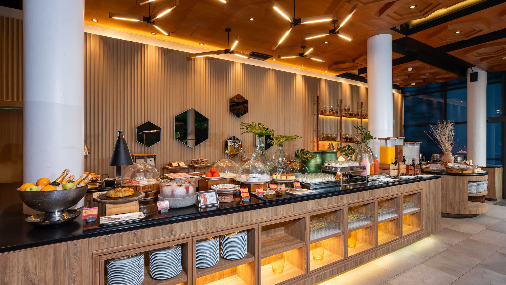 Modern hotel buffet breakfast with fresh fruits, pastries, and juices.