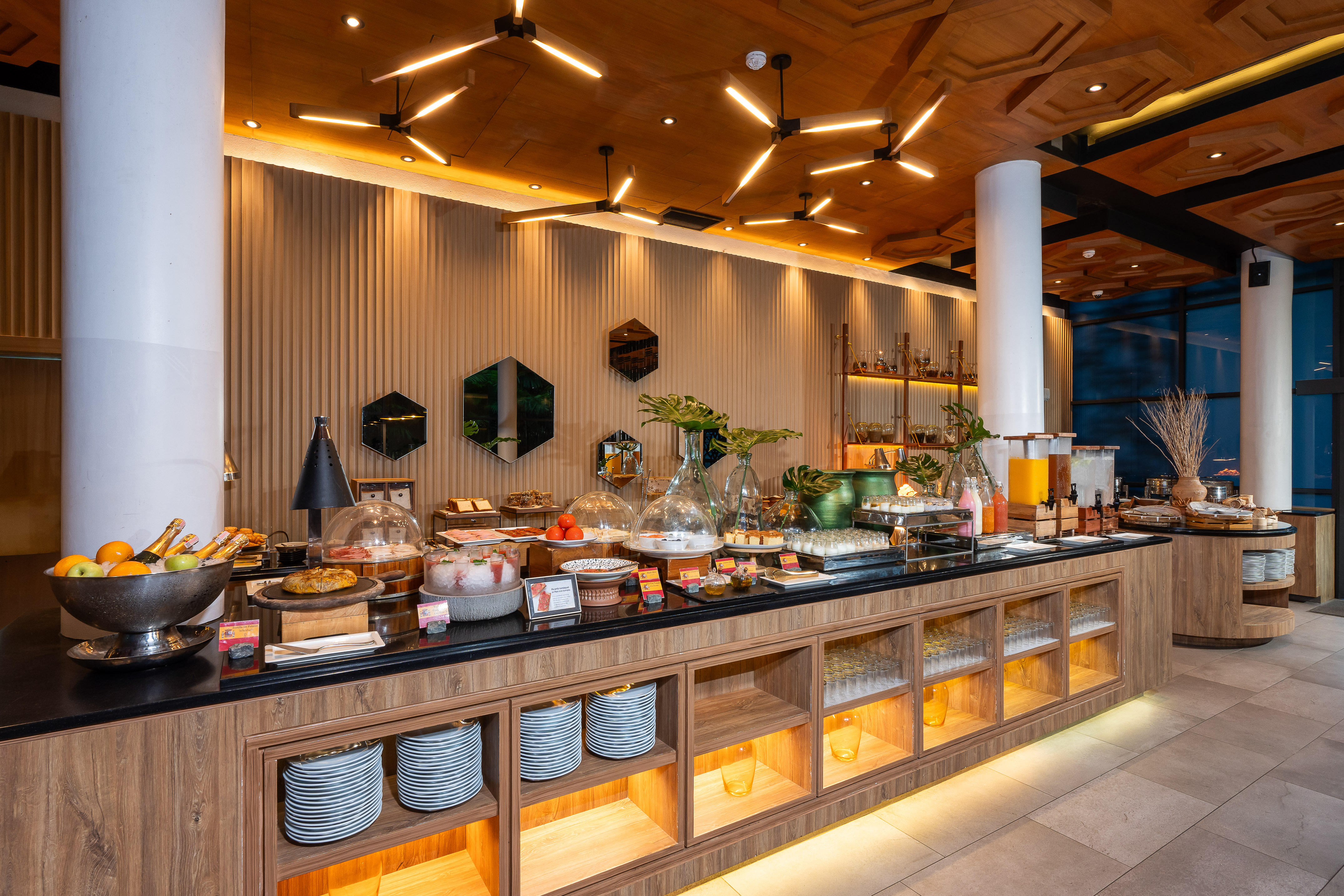 Modern hotel buffet breakfast with fresh fruits, pastries, and juices.