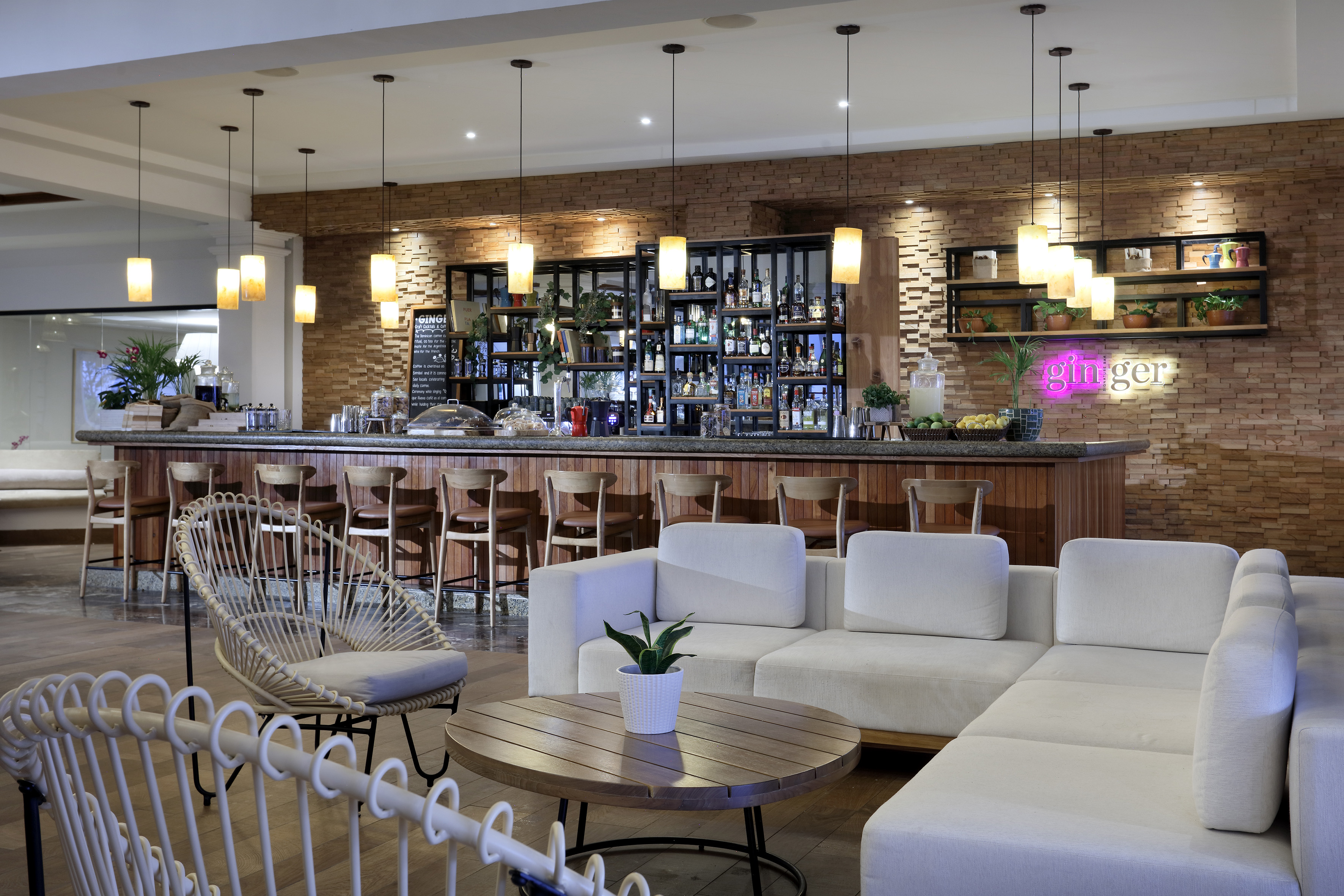 Modern hotel bar lounge with wooden counter, brick wall, and comfortable seating.