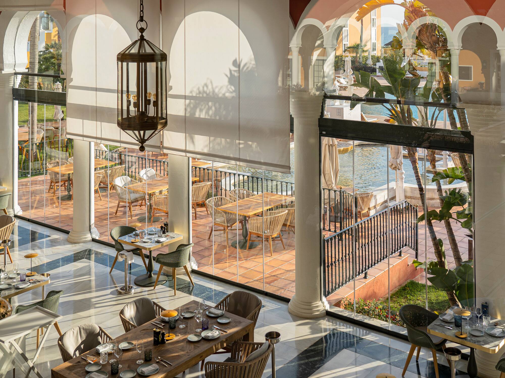 a room with tables and chairs and a pool outside