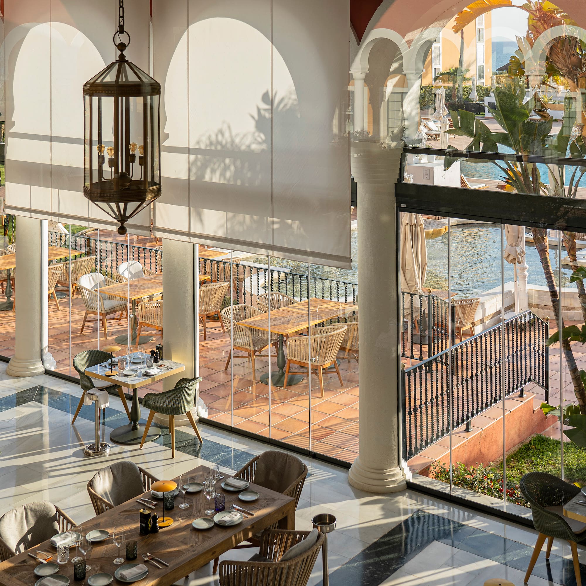 a room with tables and chairs and a pool outside