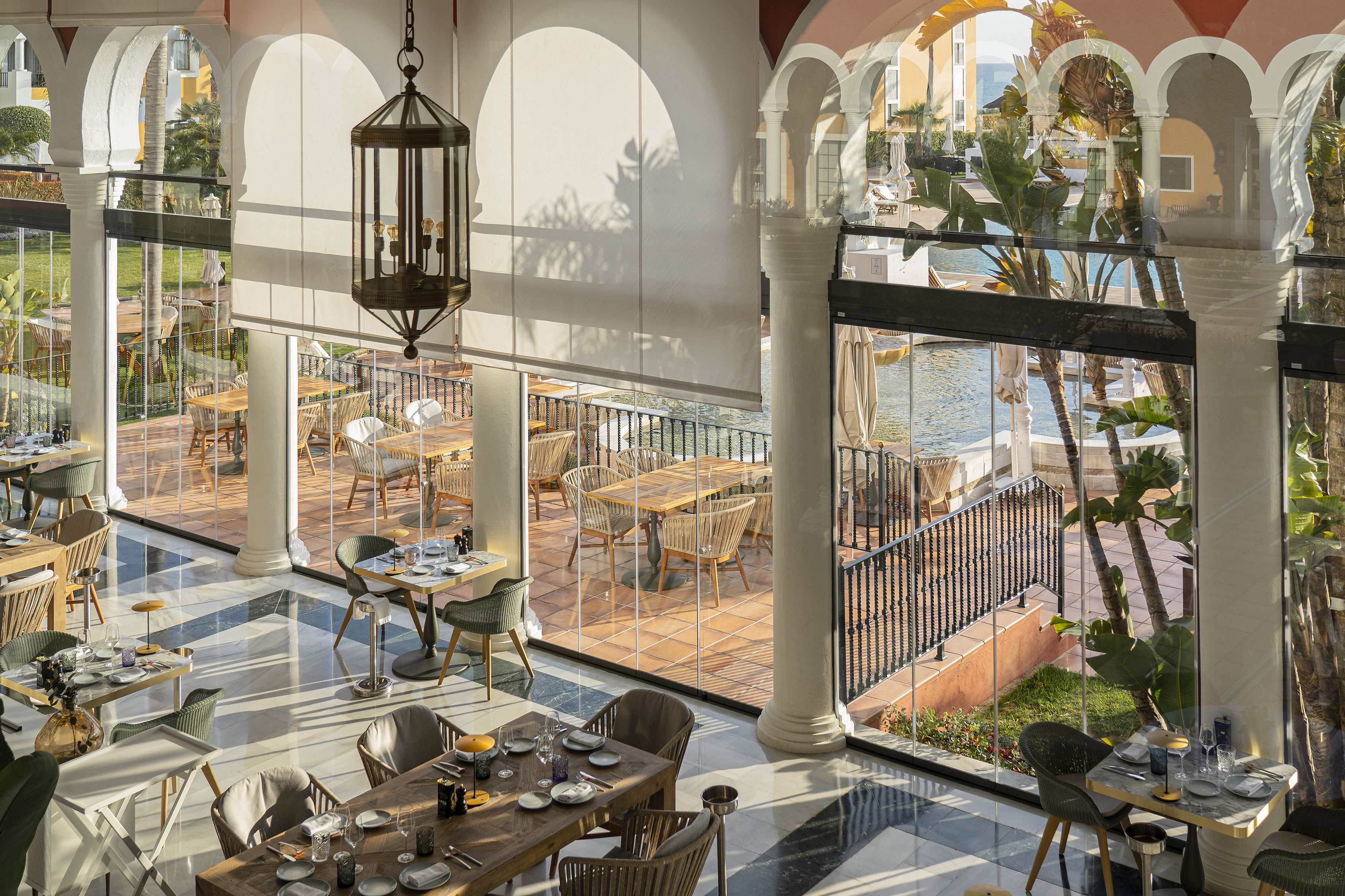 a room with tables and chairs and a pool outside