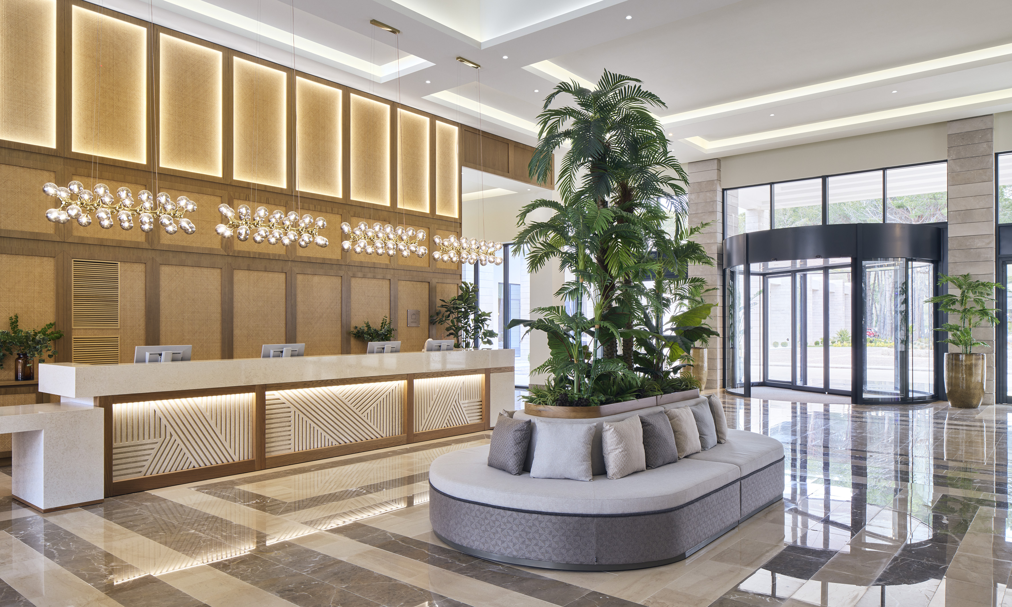 Luxury hotel lobby with modern reception, tropical plants, and elegant lighting.