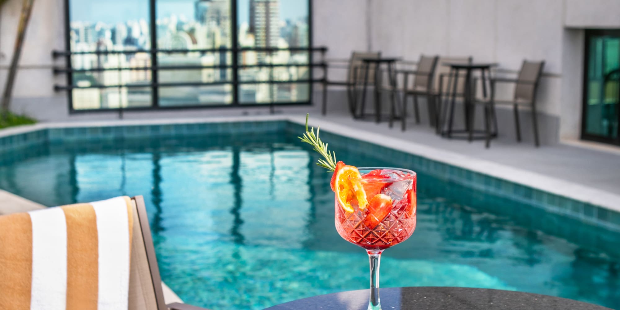 a drink and food on a table by a pool