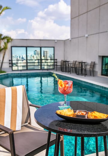 a drink and food on a table by a pool
