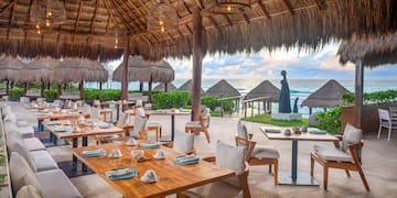 a restaurant with tables and chairs and straw umbrellas