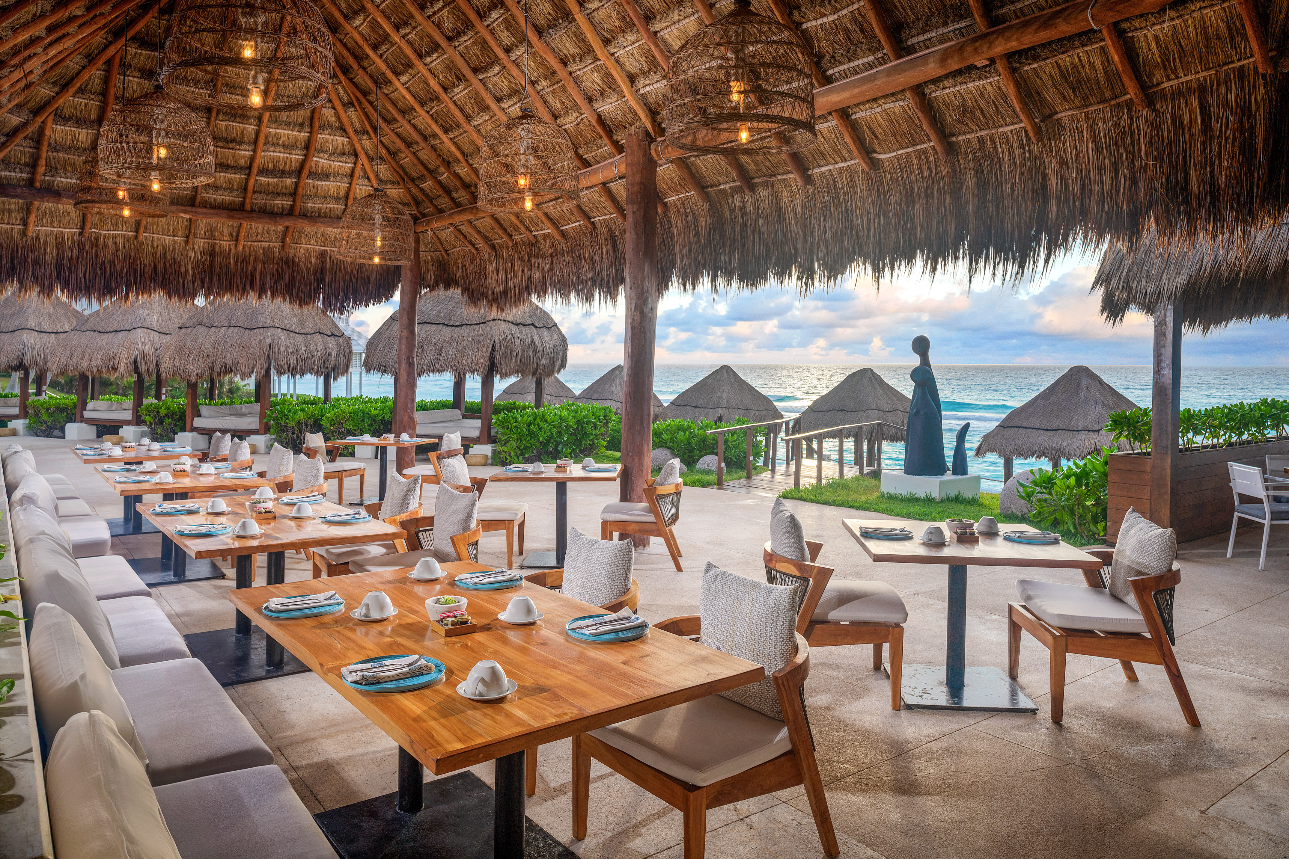 a restaurant with tables and chairs and straw umbrellas