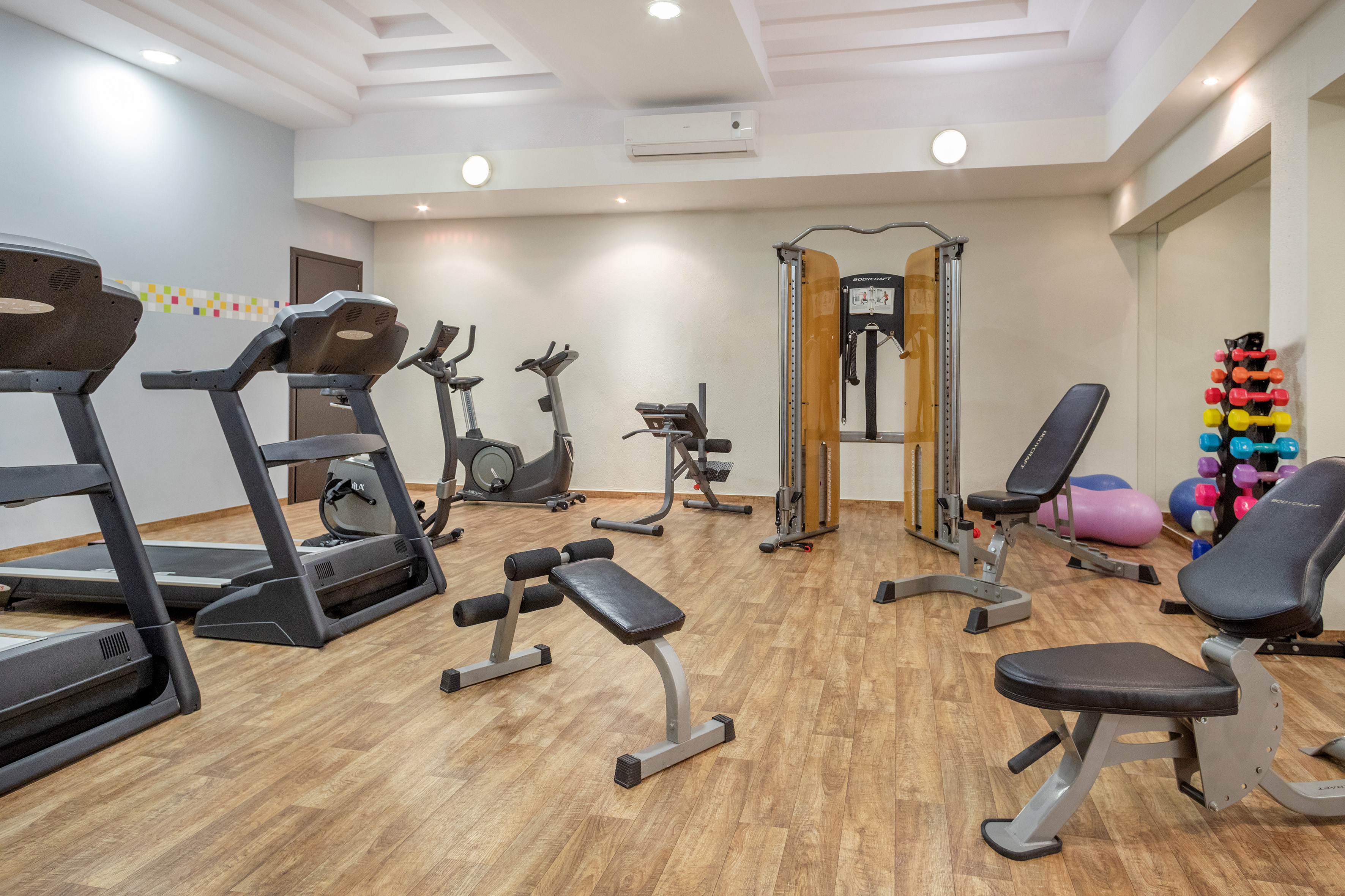 Well-equipped hotel gym with treadmills, exercise bikes, weight benches, and dumbbells.