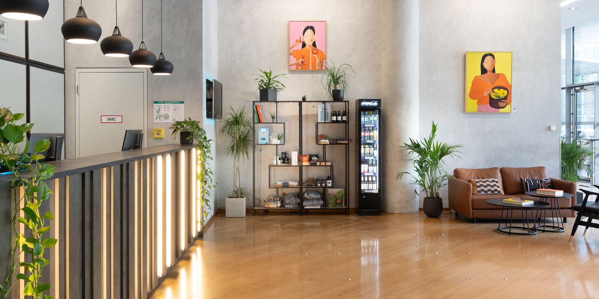 Contemporary office lobby with reception desk, lounge, colorful art, and plants.