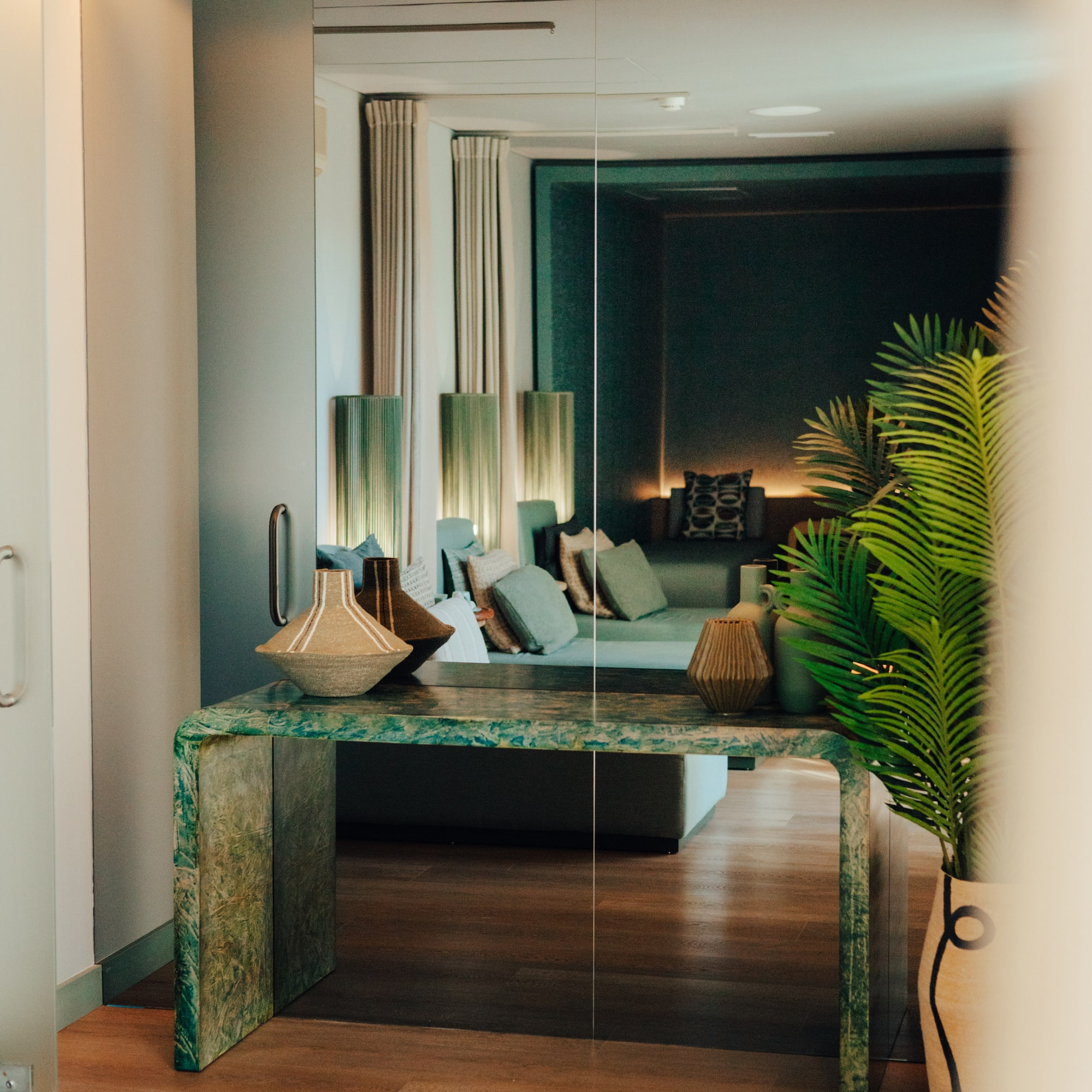 Green marble console table with vases reflecting modern lounge interior.