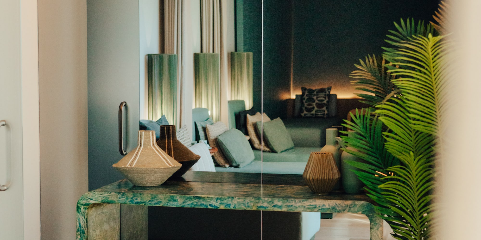 Green marble console table with vases reflecting modern lounge interior.