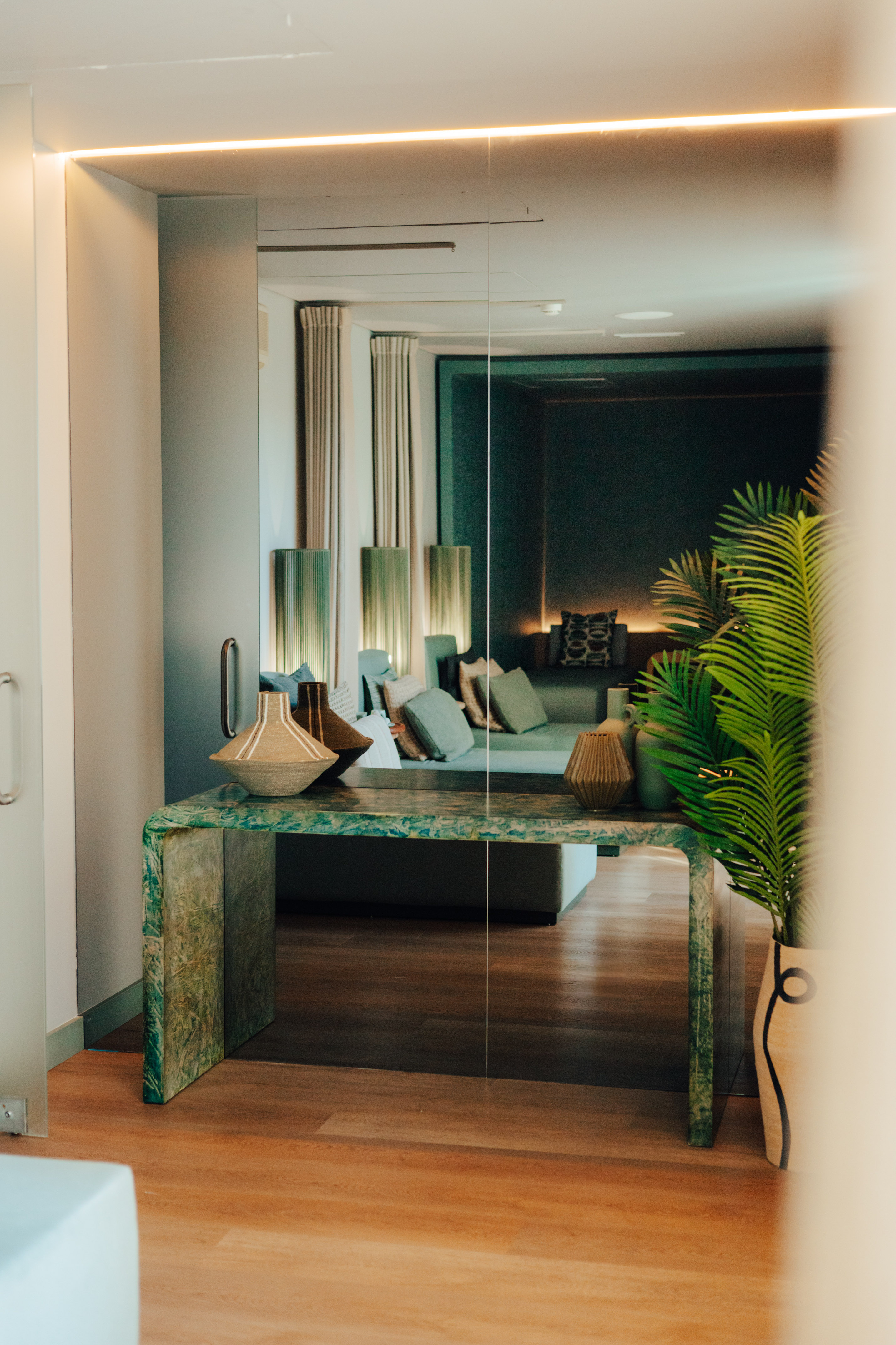 Green marble console table with vases reflecting modern lounge interior.