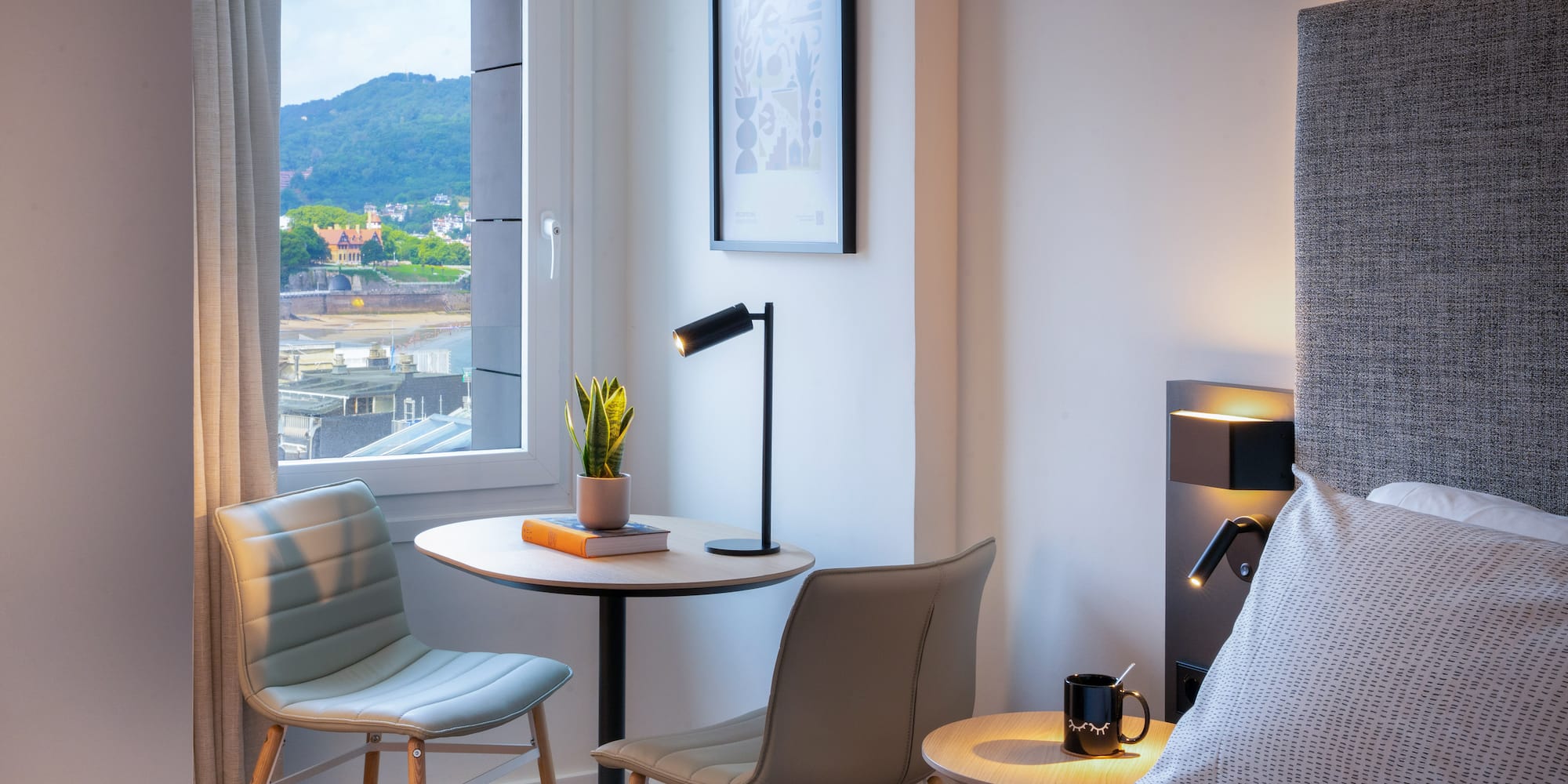 Habitación de hotel moderna con vista al mar, mesa y sillas.