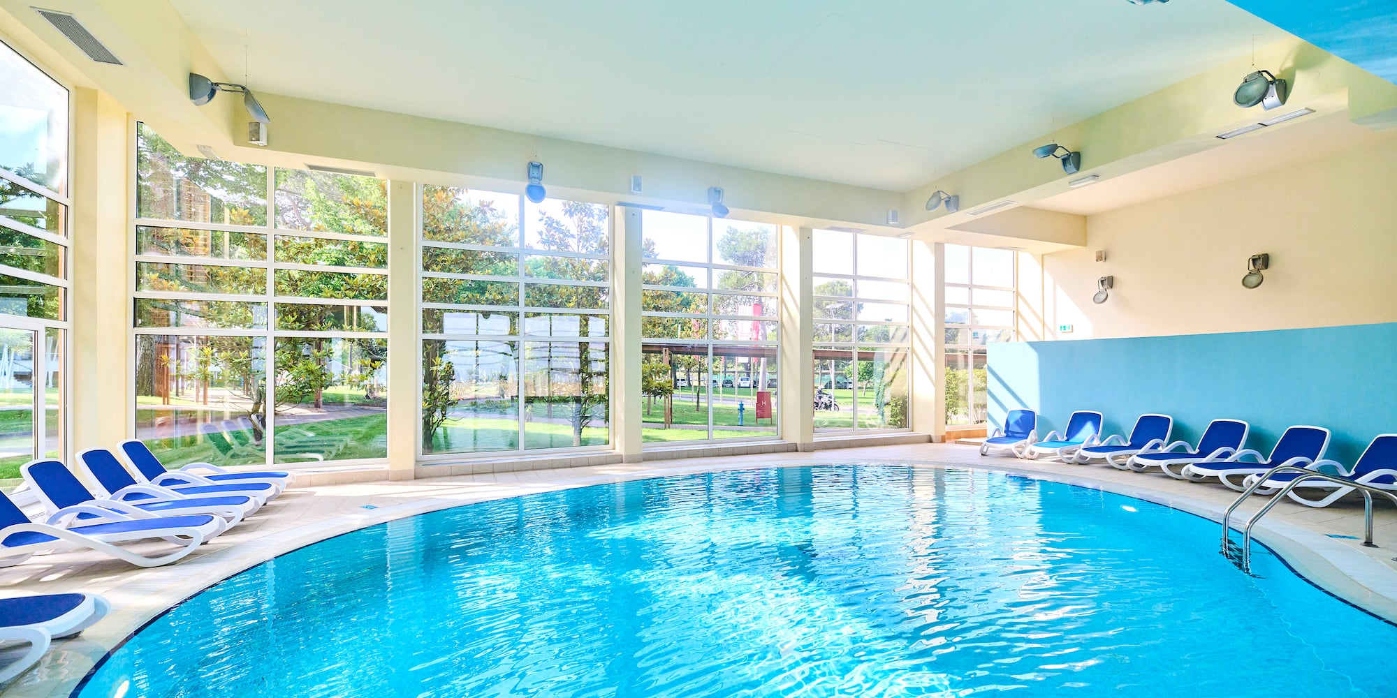a swimming pool with chairs in a room with windows