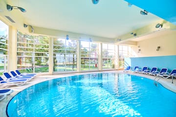 a swimming pool with chairs in a room with windows