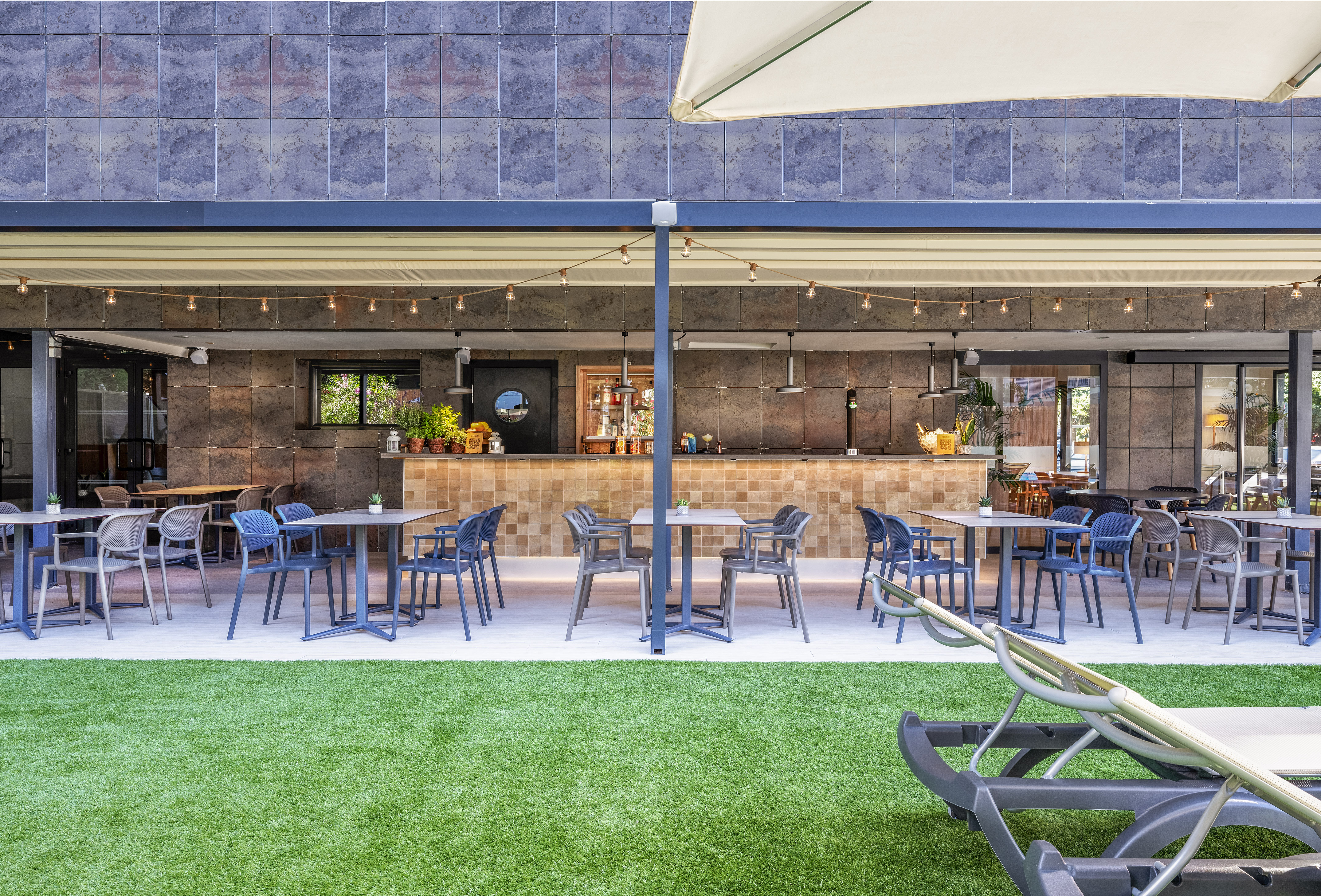 Outdoor hotel bar and dining patio with modern furniture, artificial grass.