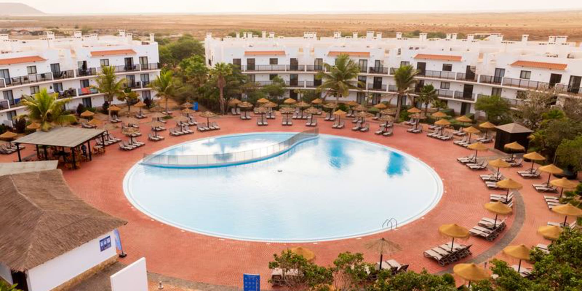 a pool with umbrellas and chairs in front of buildings